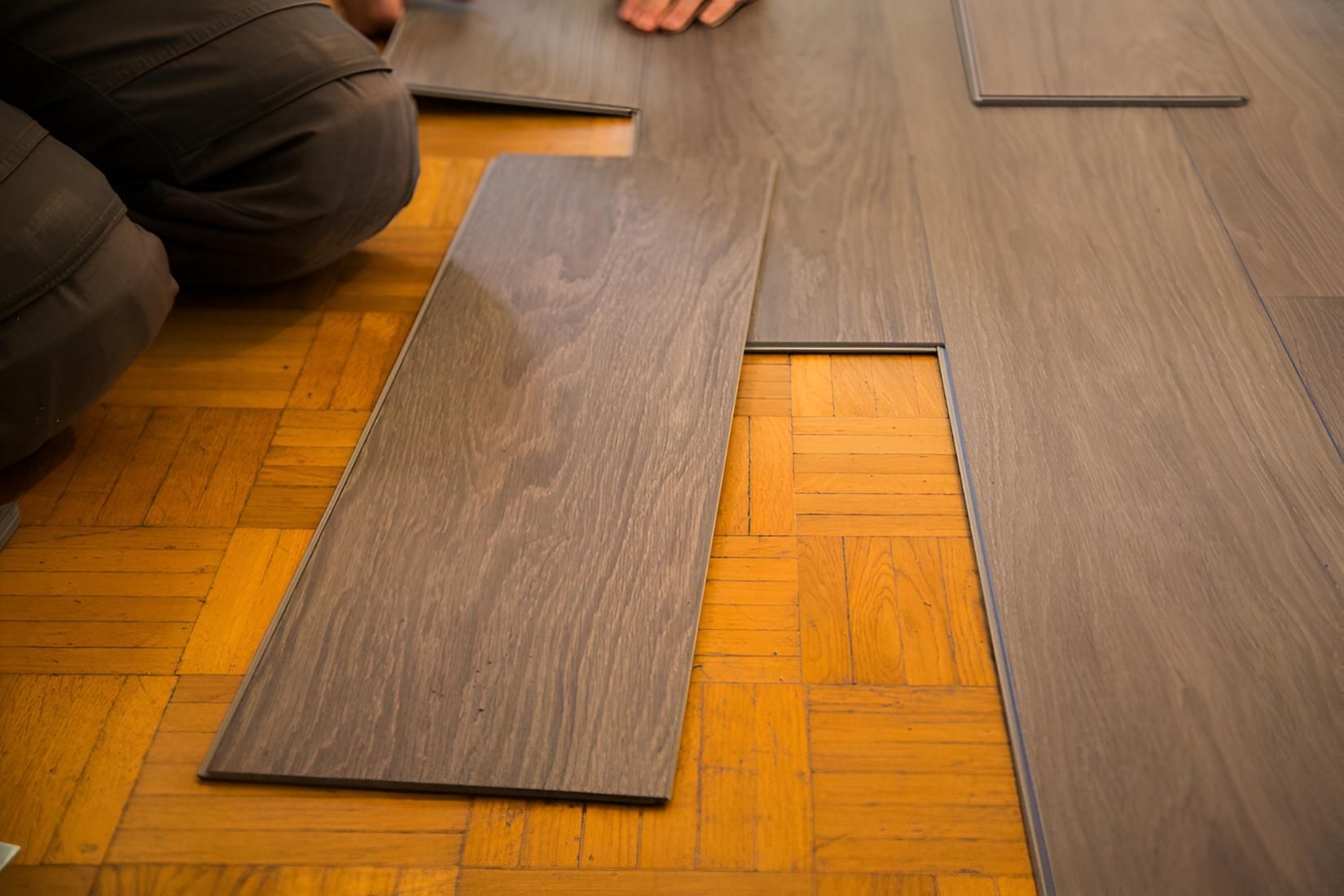 Person is Installing a Wooden Floor in a Room — Affordable Carpets & Mats in Caboolture, QLD
