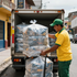 Repartidor descargando paquetes envueltos de un camión en una calle de la ciudad.