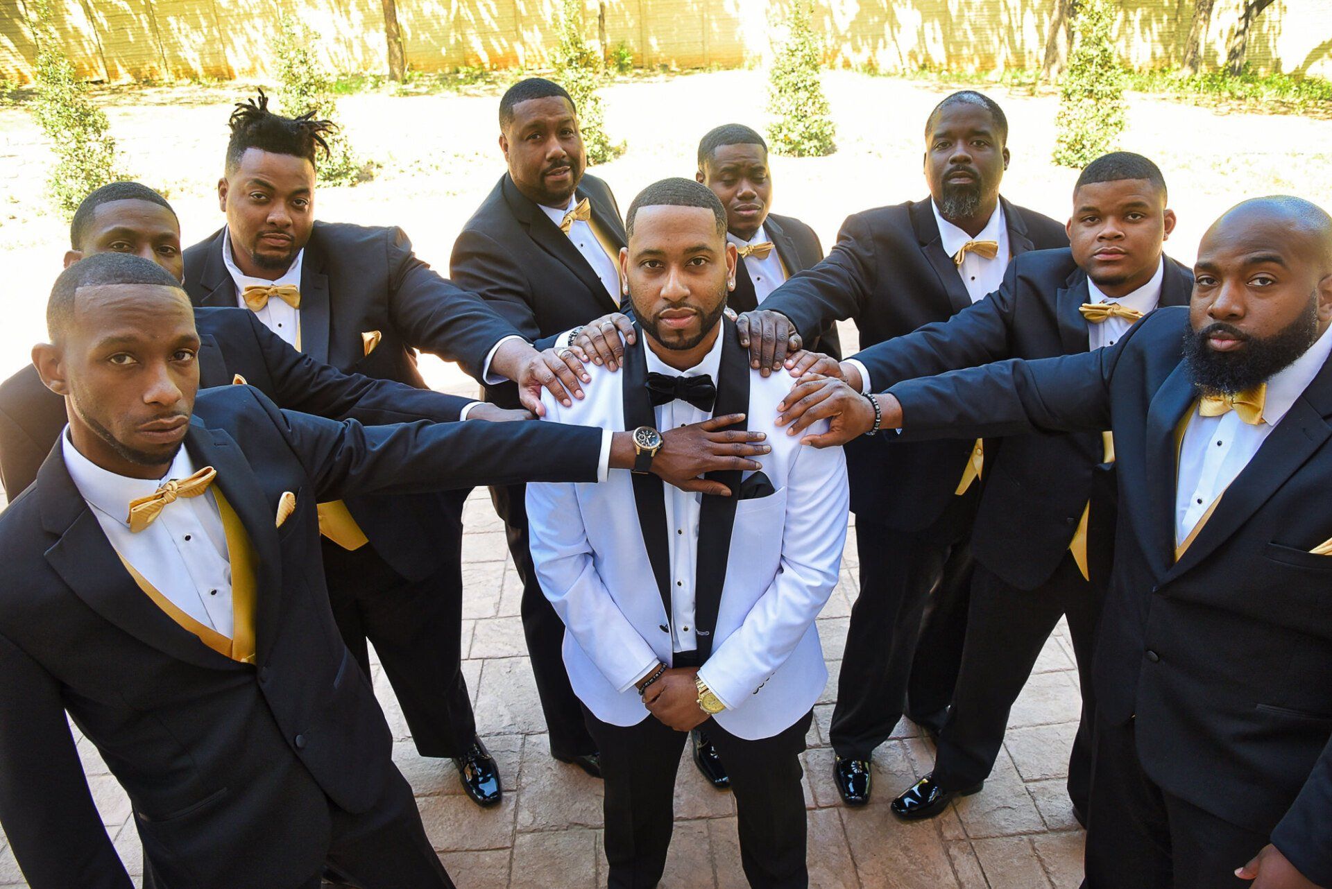 a group of men in tuxedos and bow ties are posing for a picture .