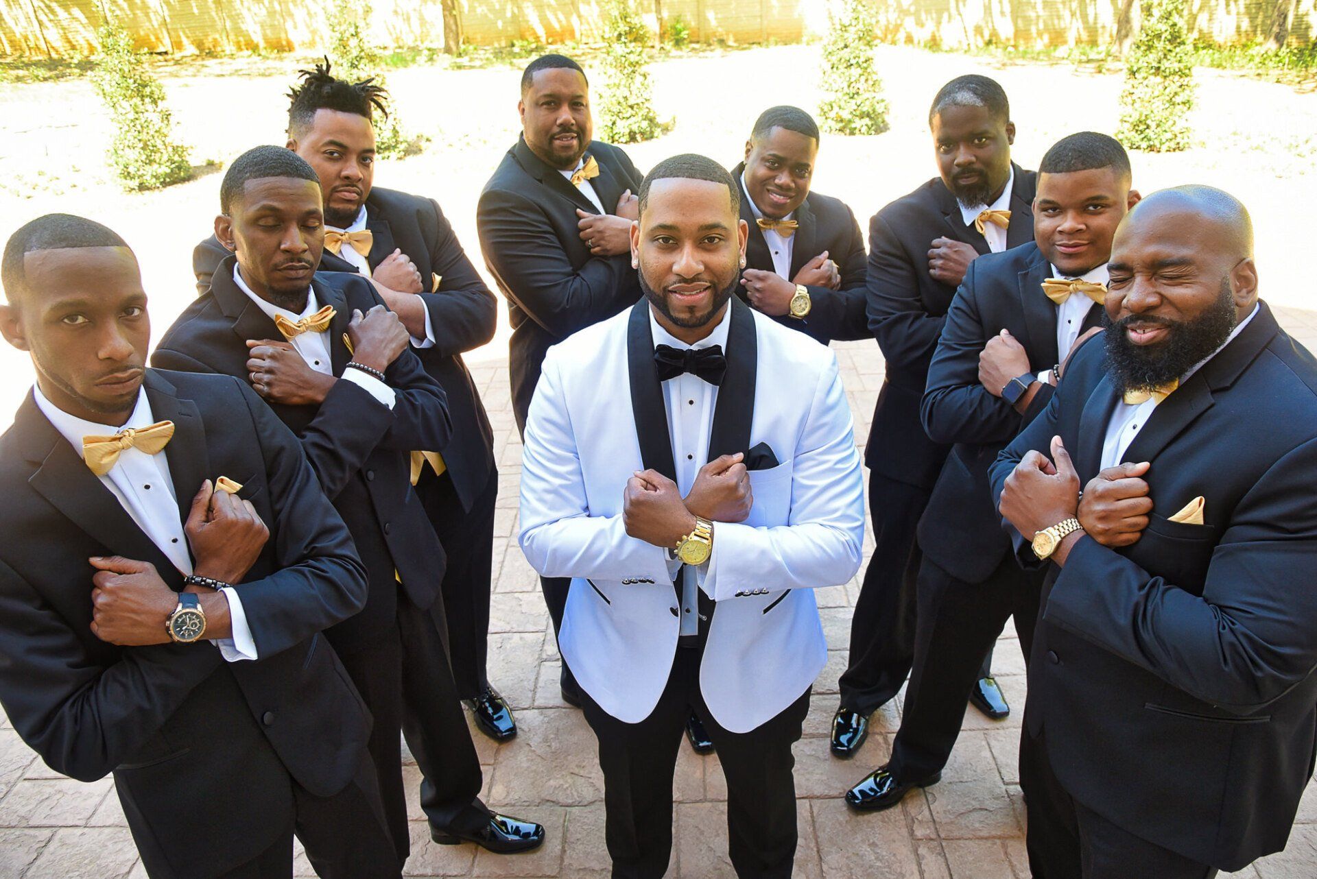 a group of men in tuxedos and bow ties are posing for a picture .