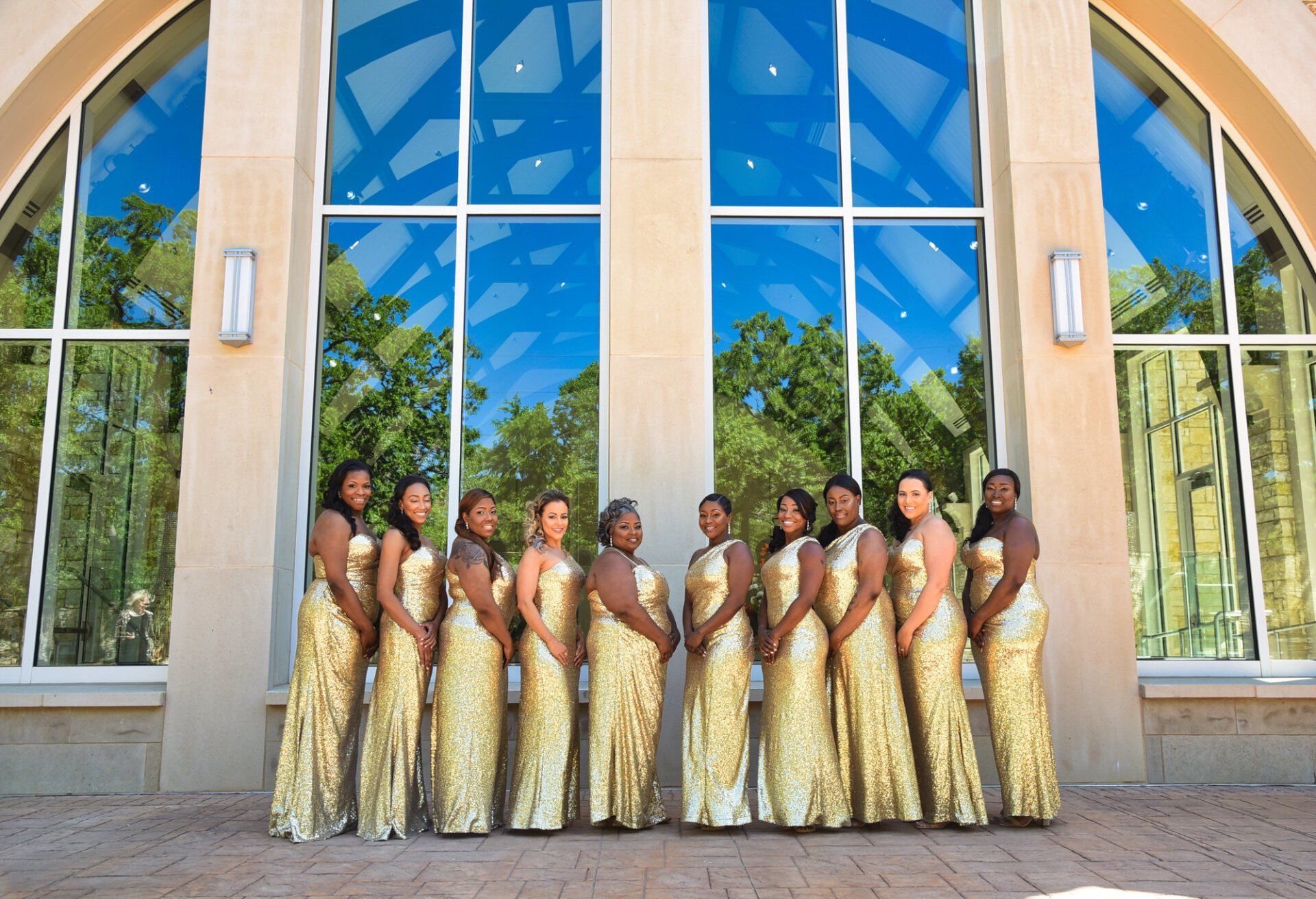 a group of women in gold dresses standing in front of a building
