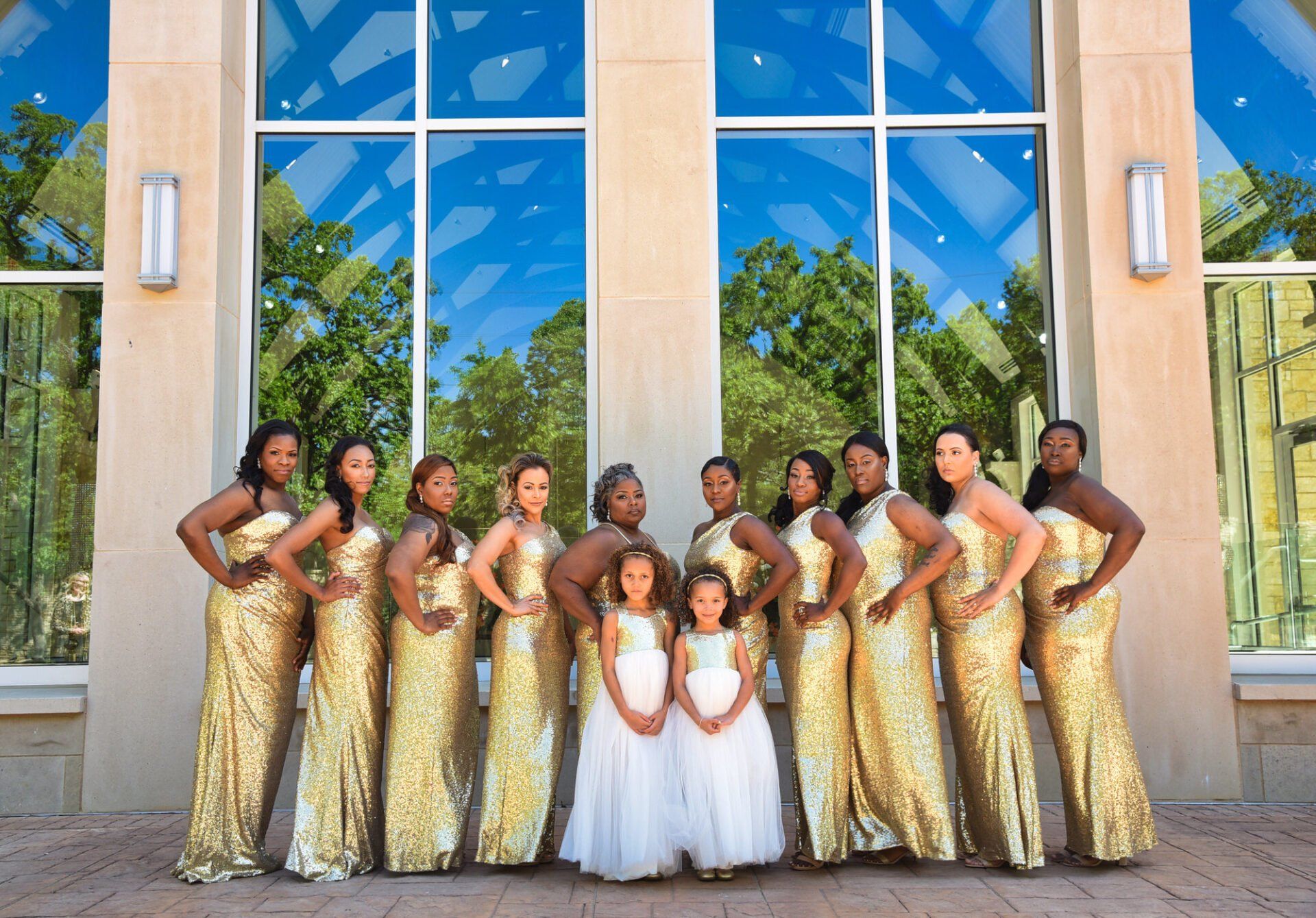 a group of women in gold sequined dresses are posing for a picture .