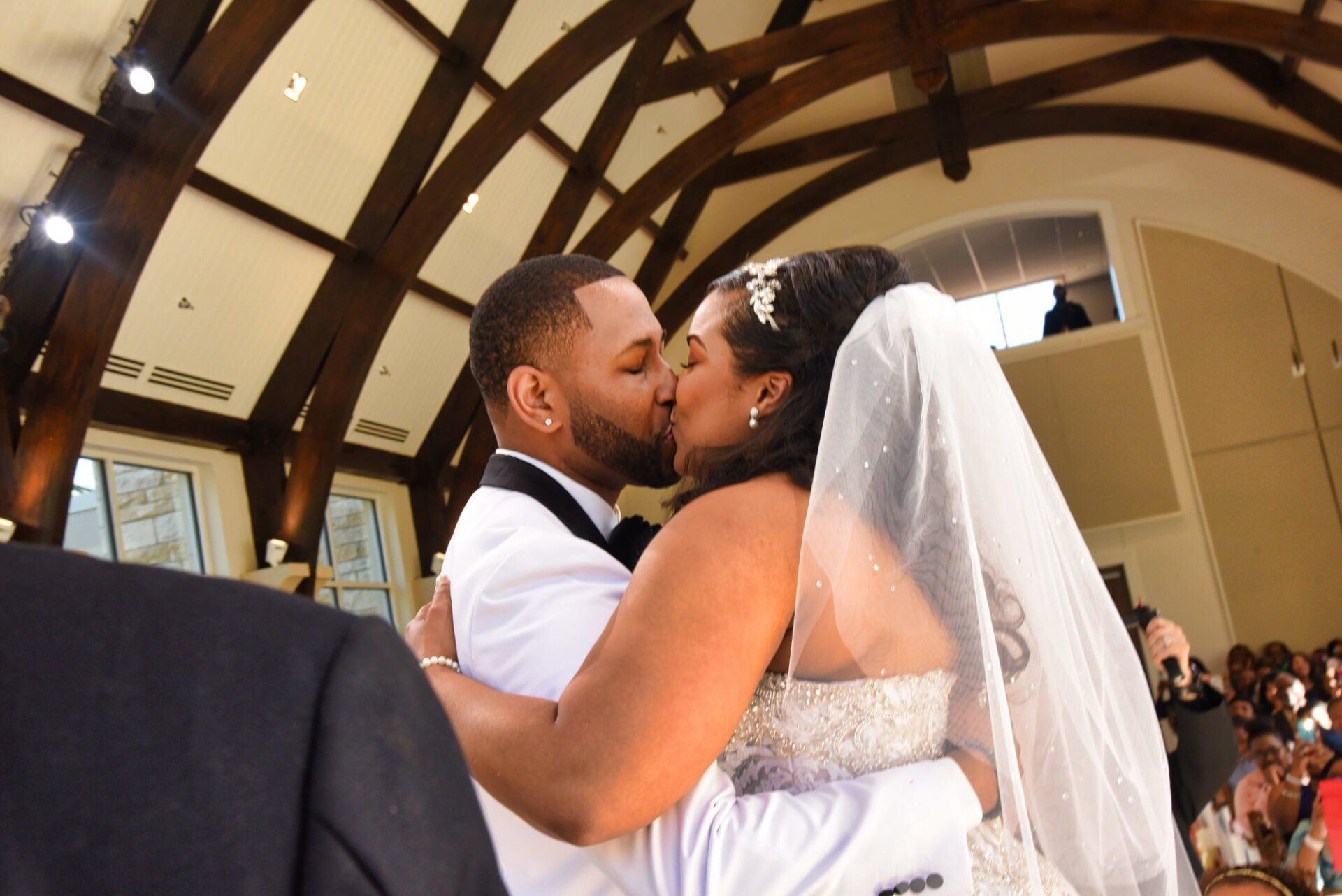 a bride and groom are kissing in a church .