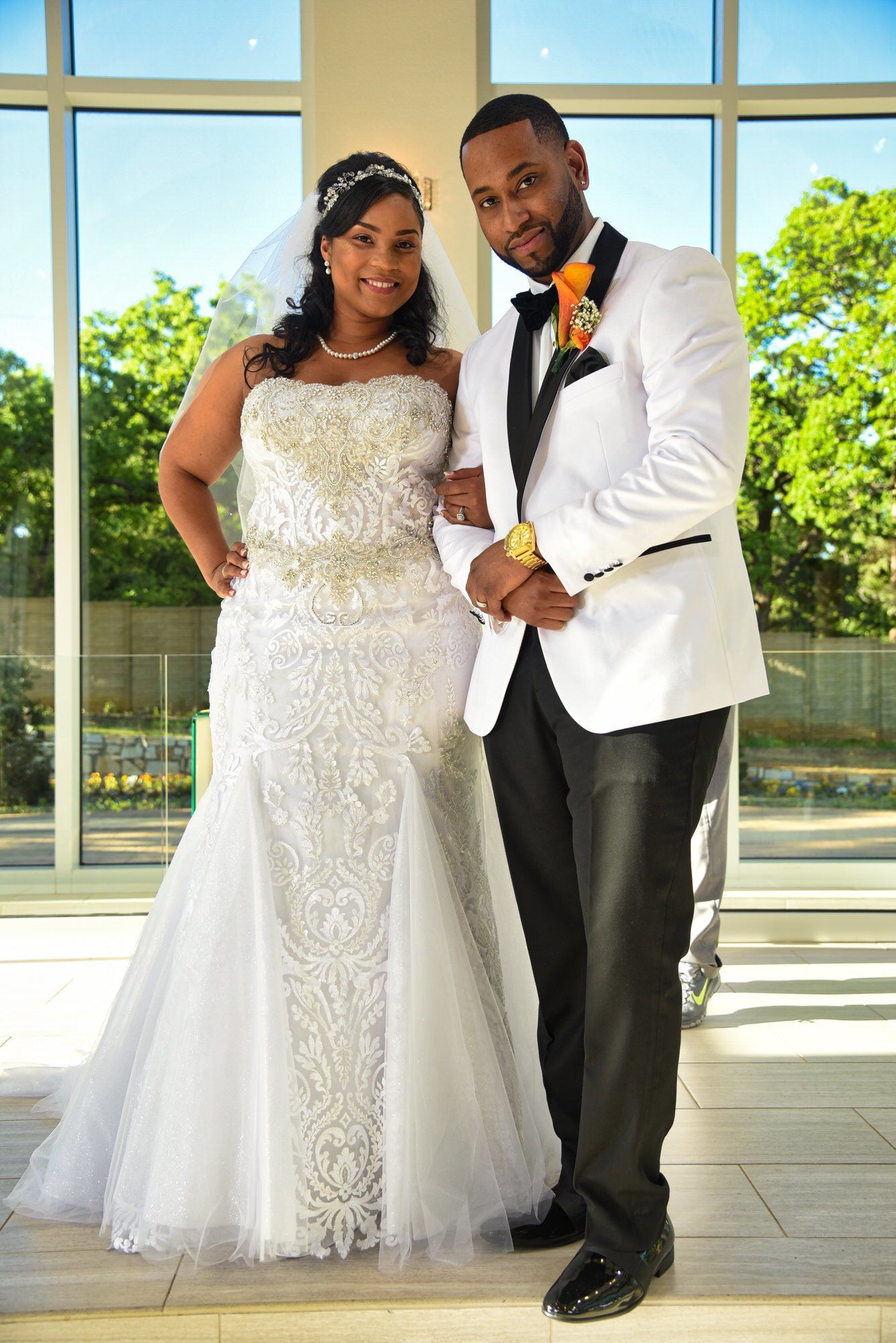 a bride and groom are posing for a picture in front of a window .