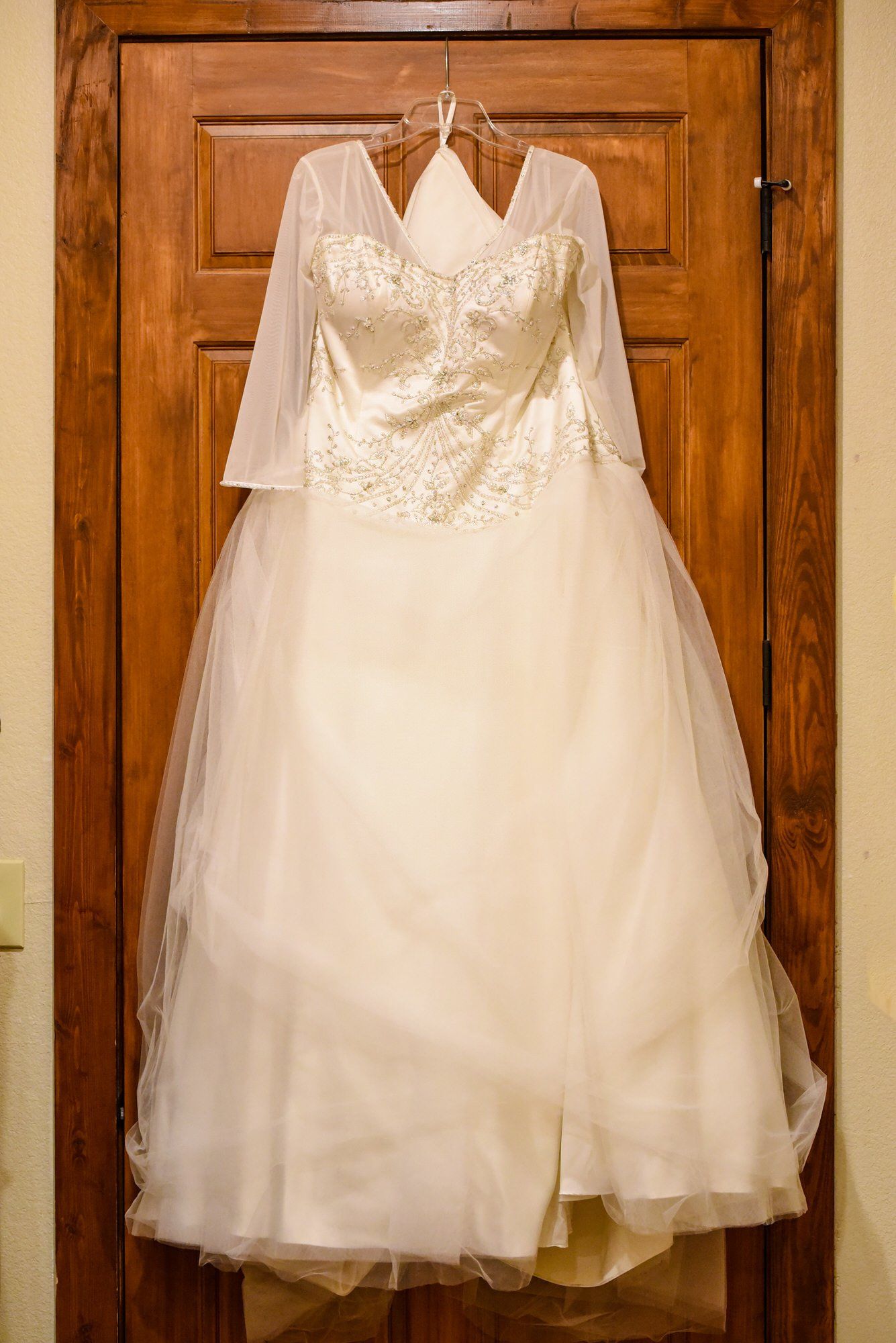 a white wedding dress is hanging on a wooden door .