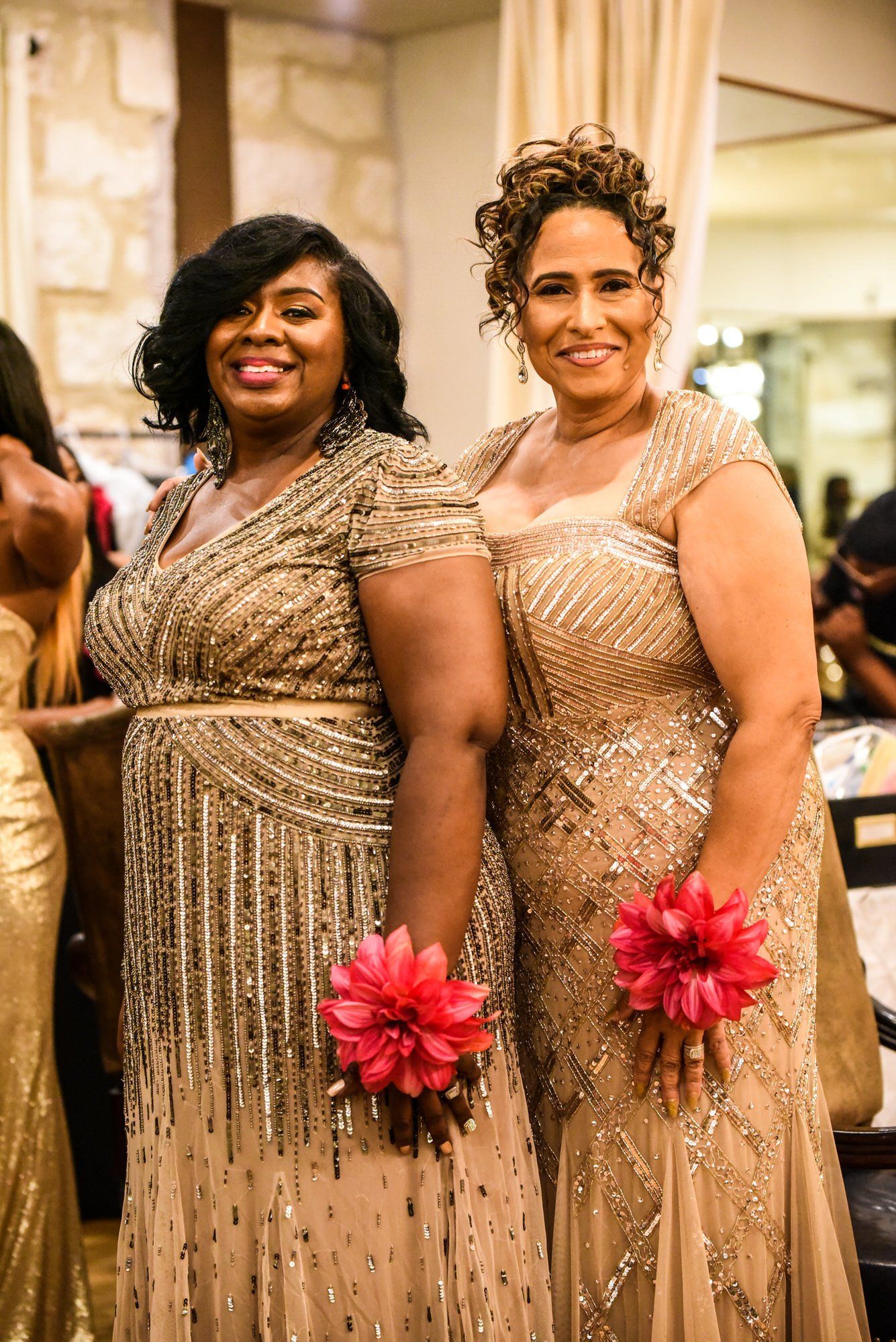 two women in dresses are standing next to each other and smiling .