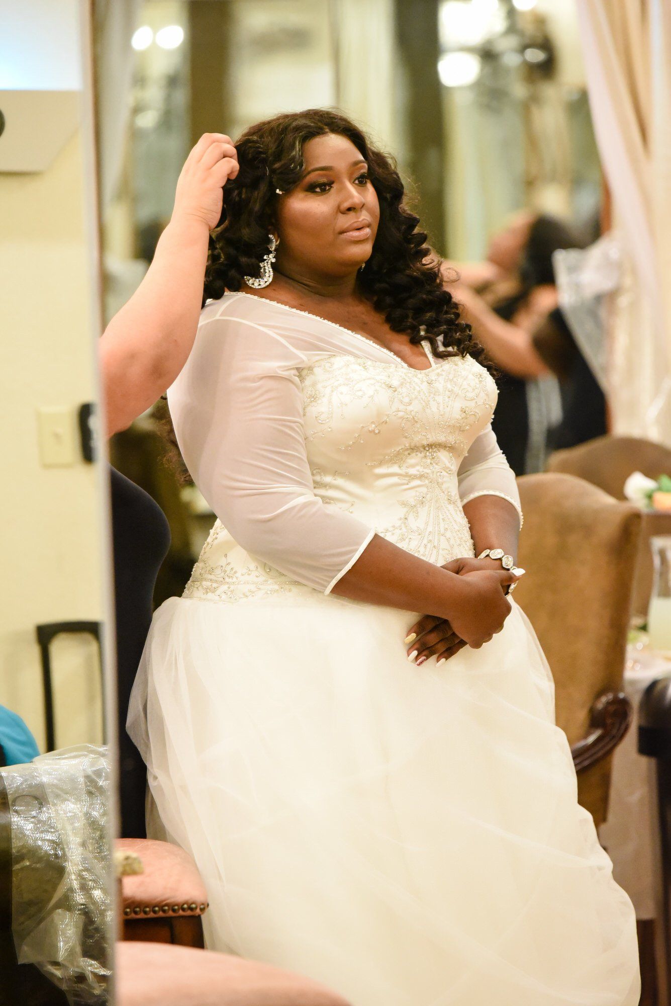 a woman in a wedding dress is getting her hair done in front of a mirror .