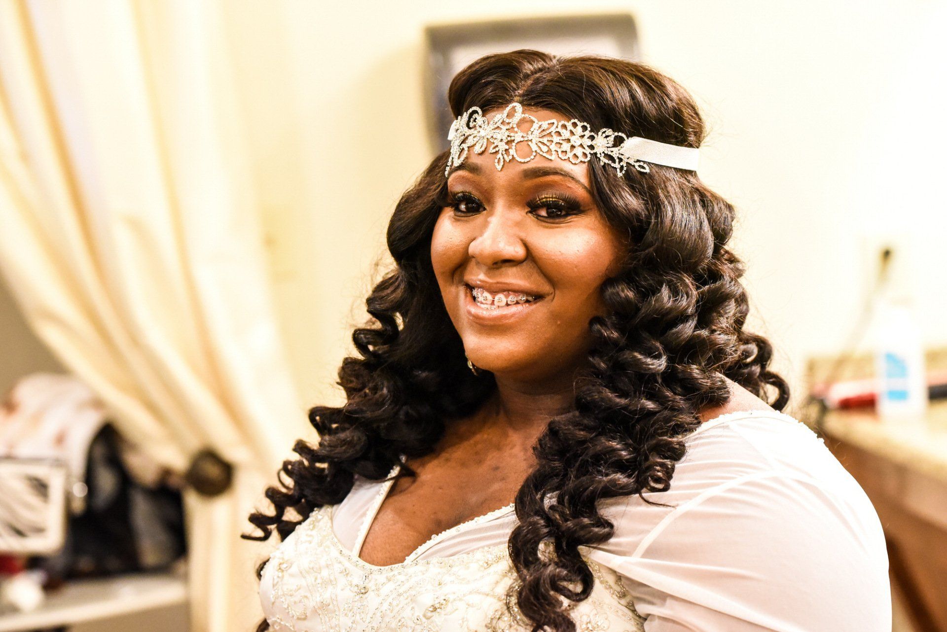 a woman in a wedding dress is wearing a headband and smiling .