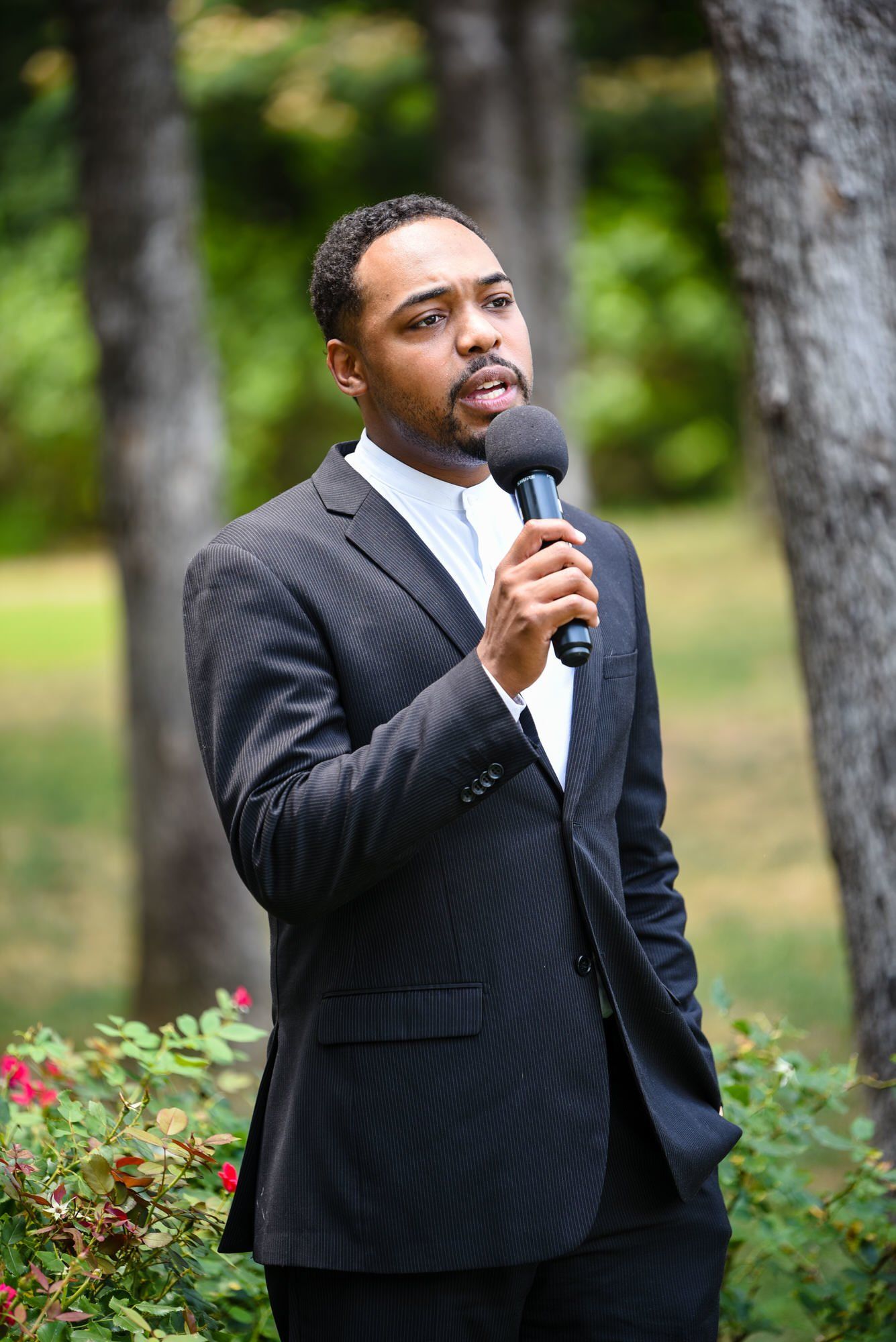 a man in a suit is holding a microphone in his hand .