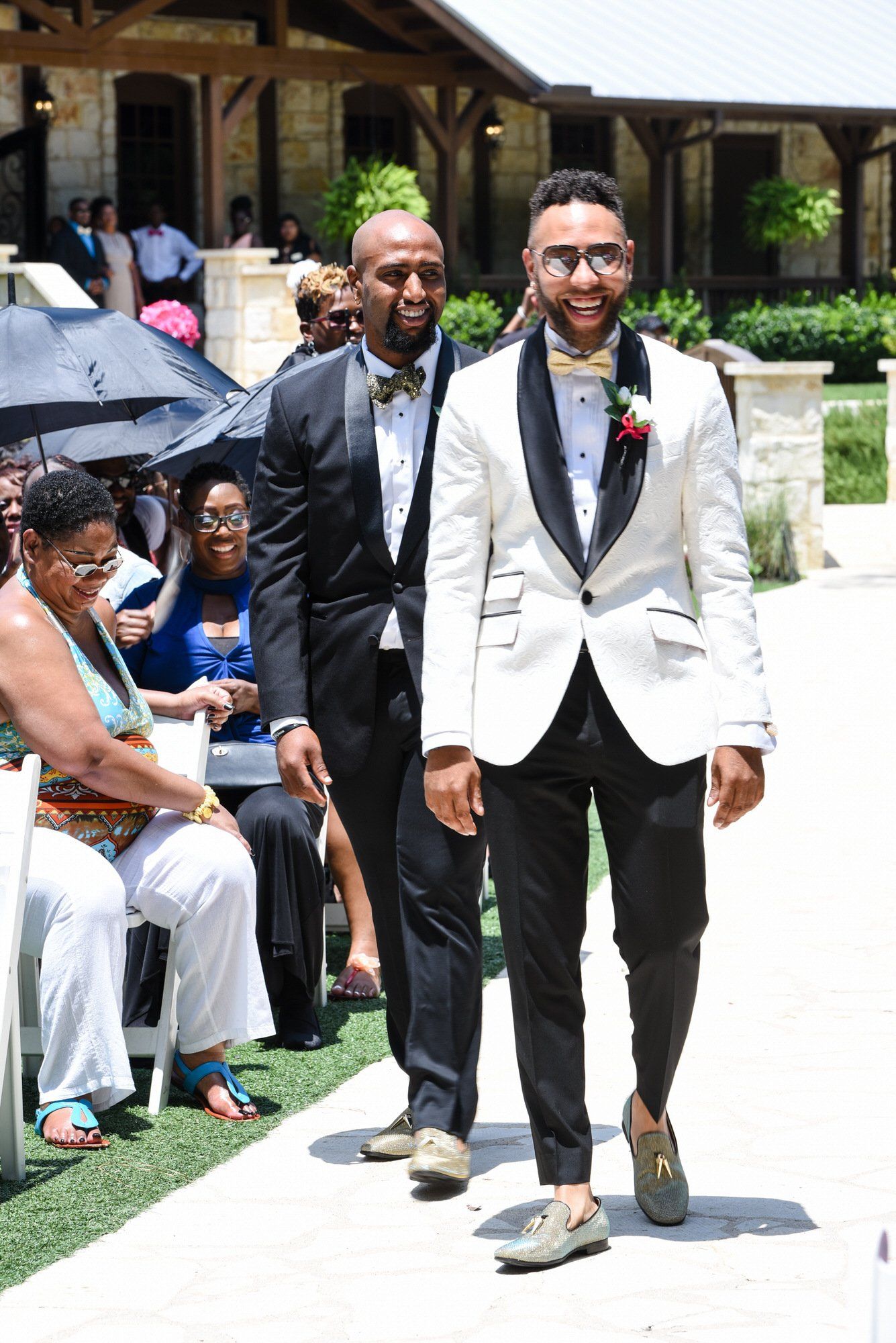 a man in a white tuxedo is walking down the aisle at a wedding .