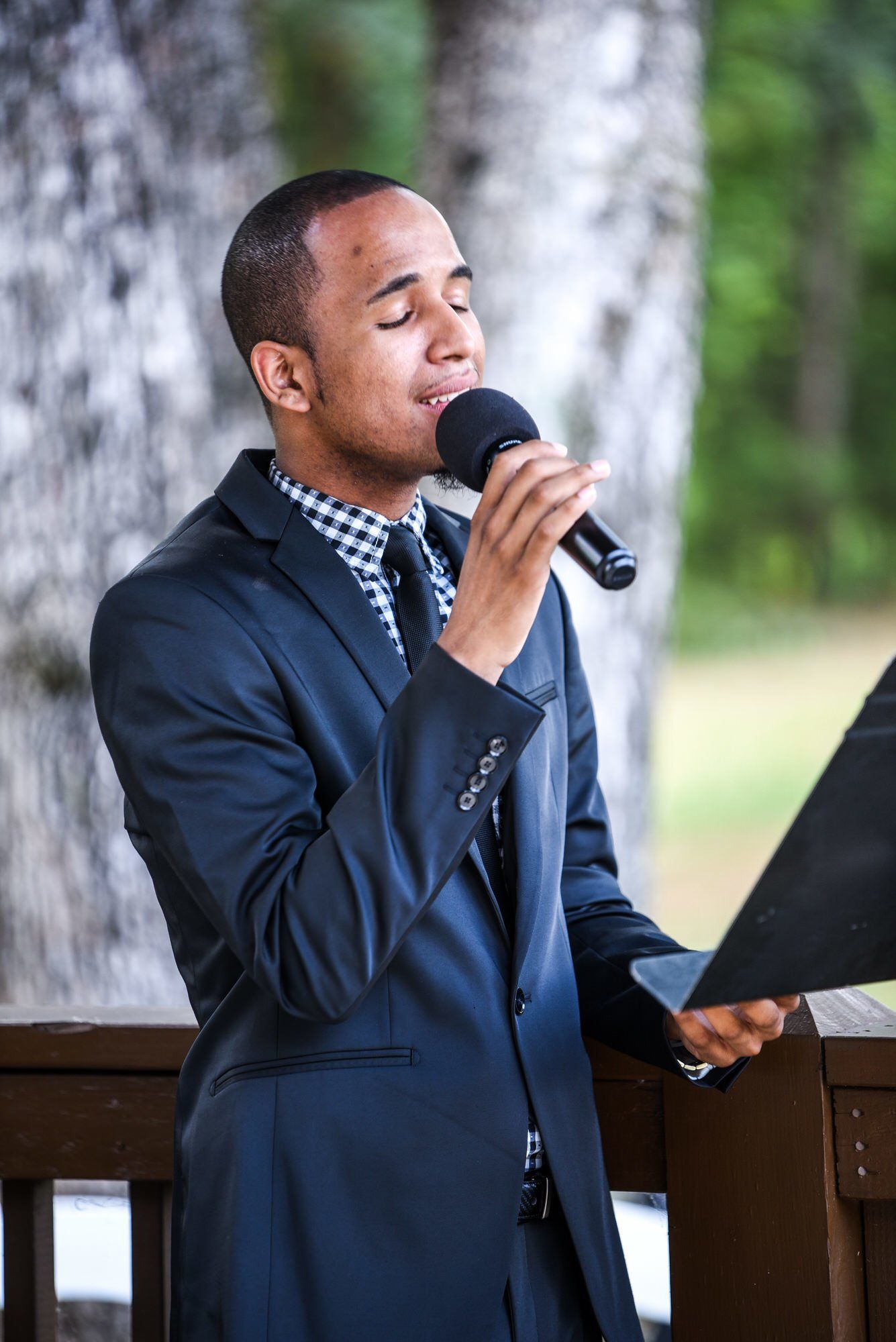 a man in a suit and tie is singing into a microphone .