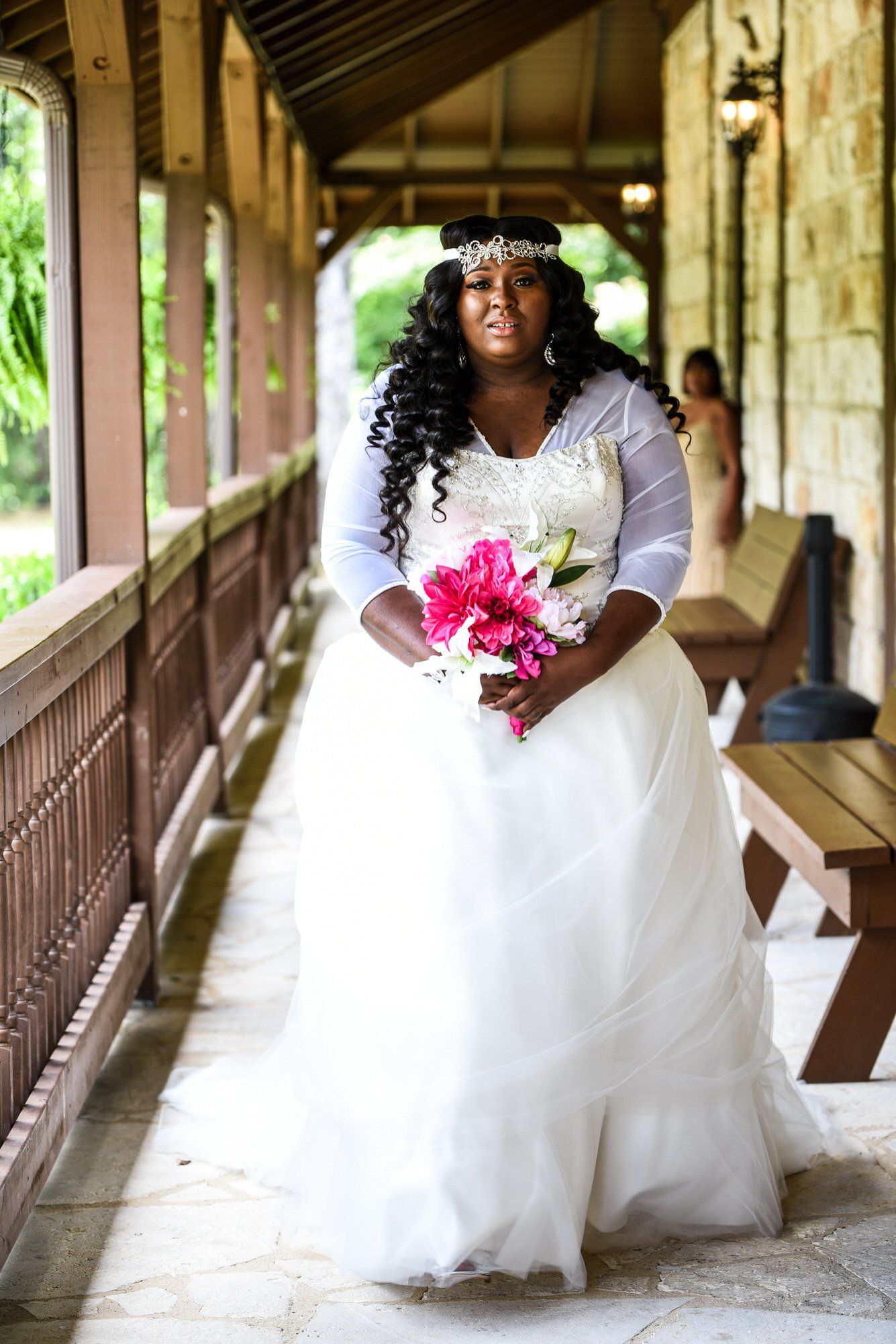 a woman in a wedding dress is holding a bouquet of pink flowers .