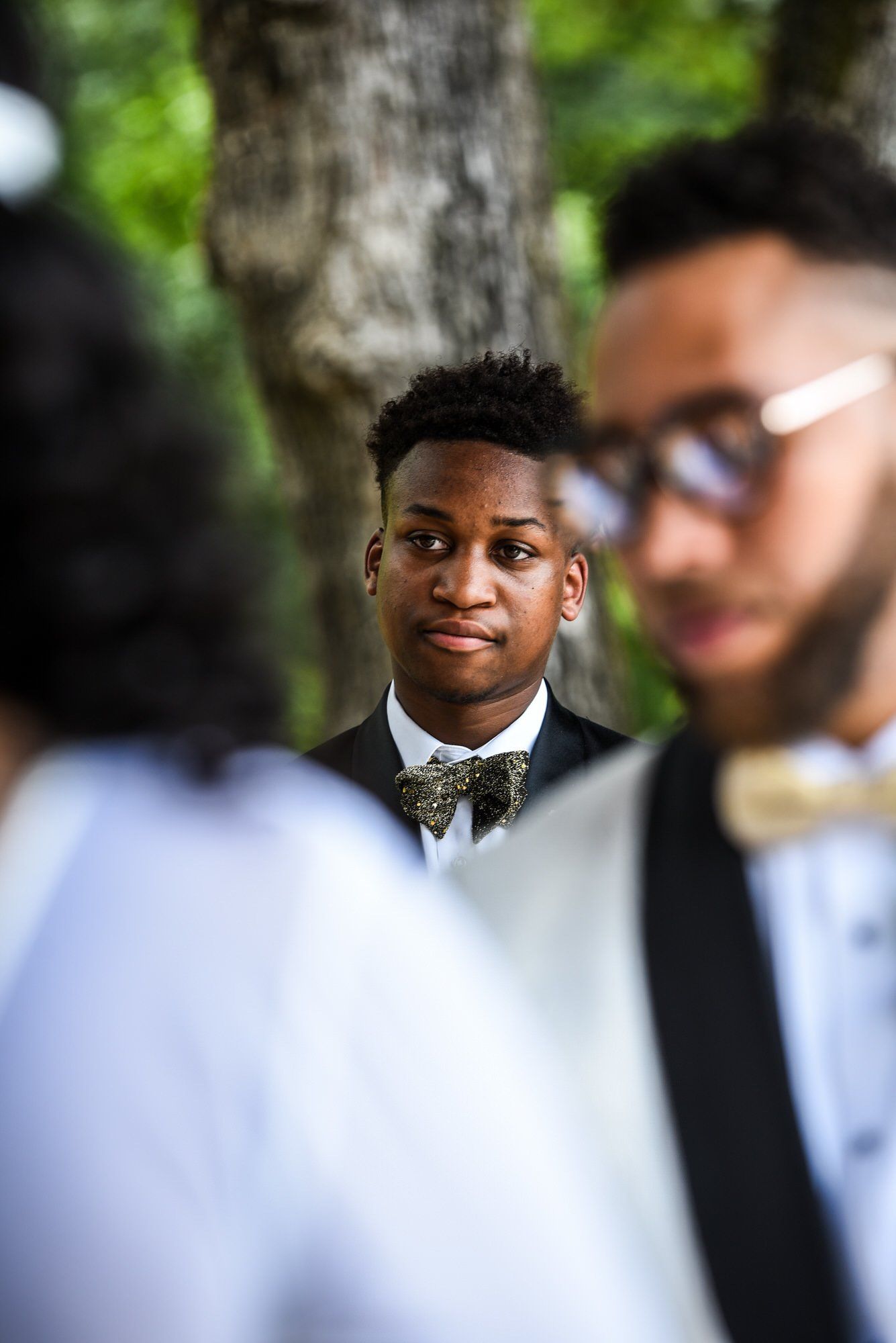a man in a tuxedo and bow tie is standing in a crowd of people .