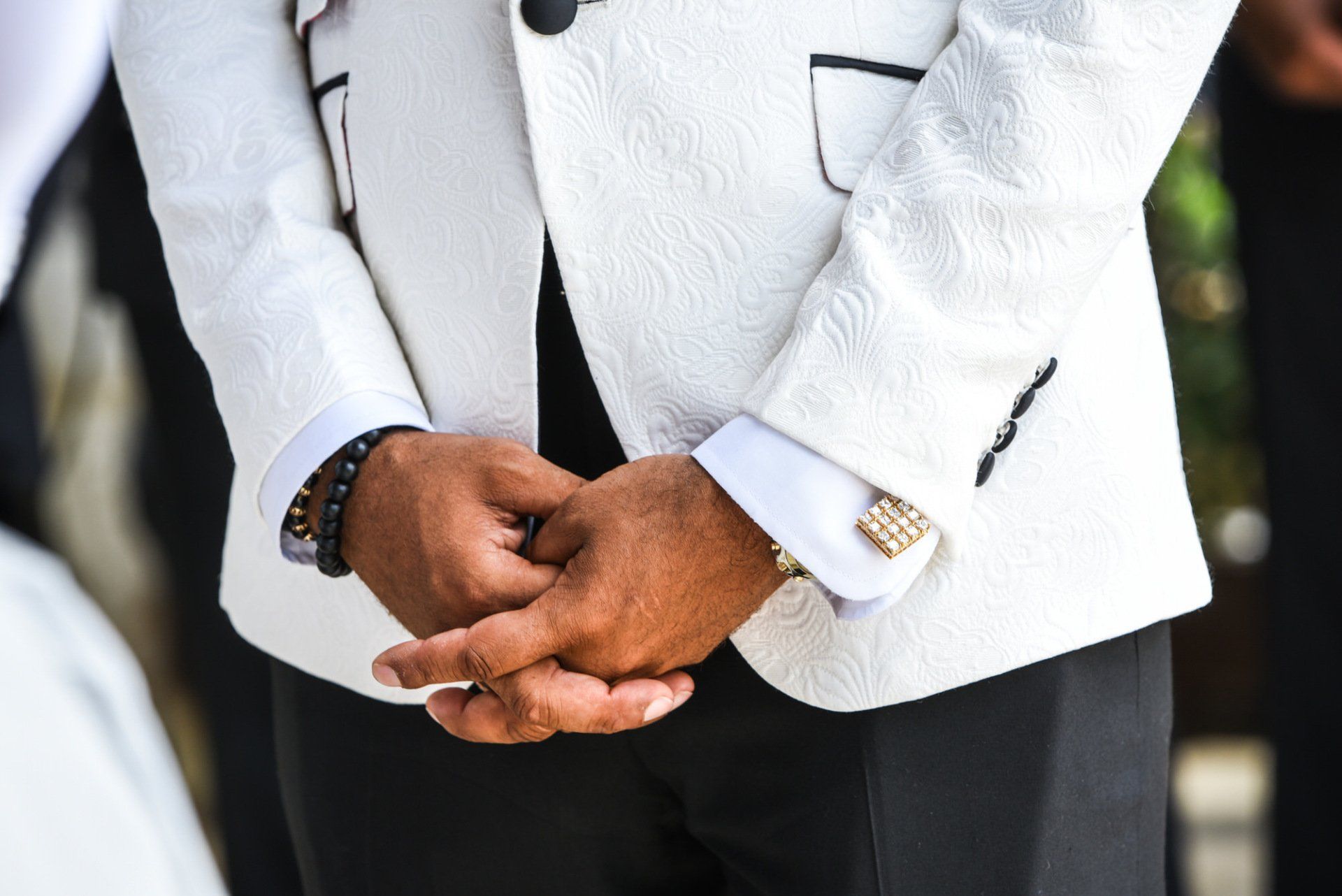 a man in a white suit is holding his hands together .
