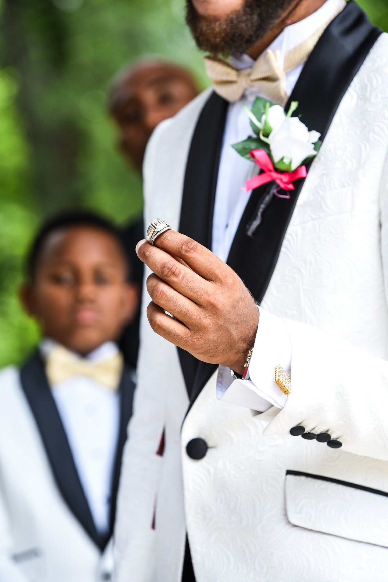 a man in a tuxedo is holding a ring in his hand