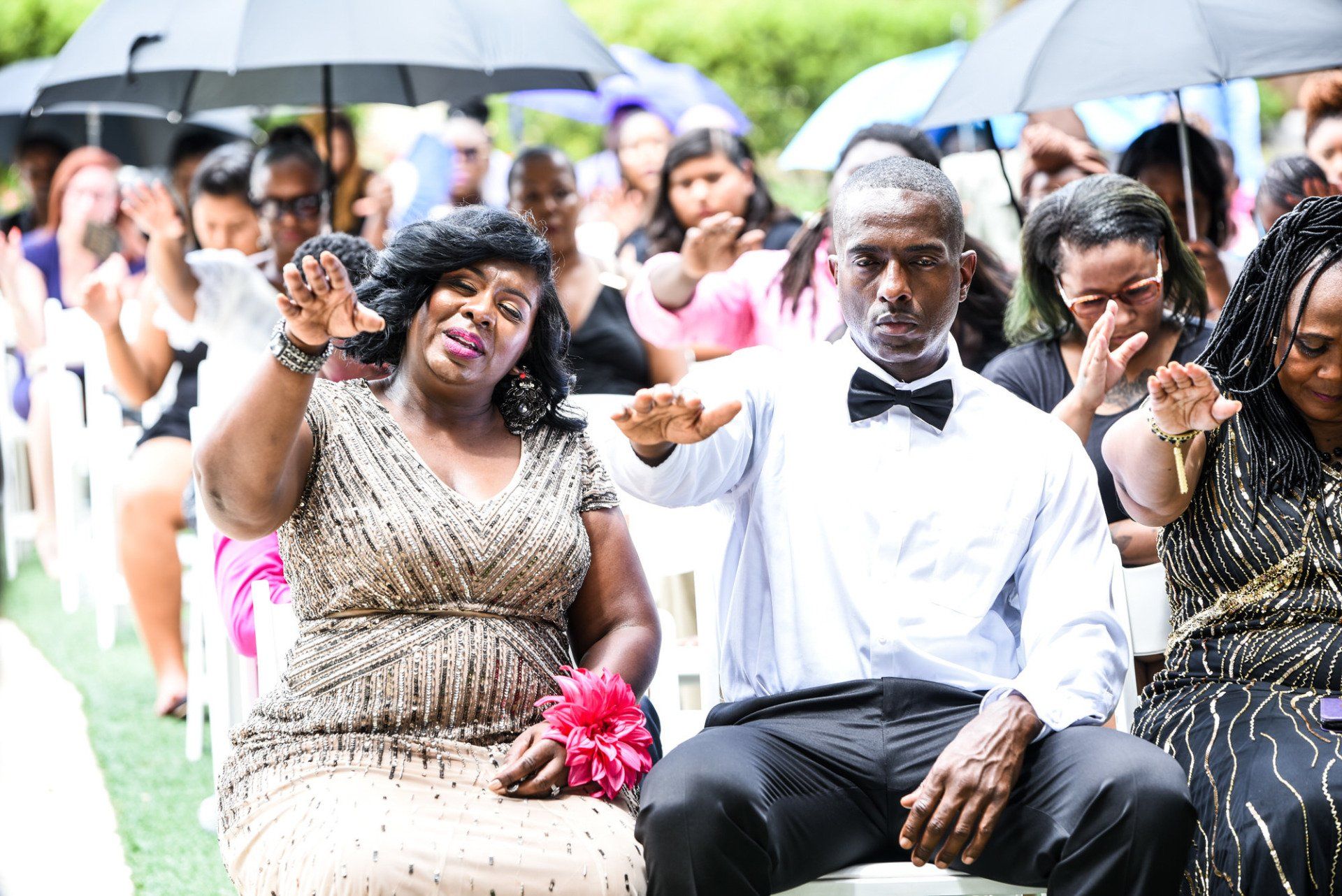 a group of people are sitting under umbrellas at a wedding ceremony .