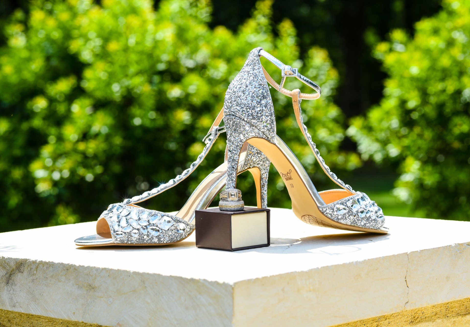 a pair of wedding shoes and a wedding ring are sitting on a ledge .