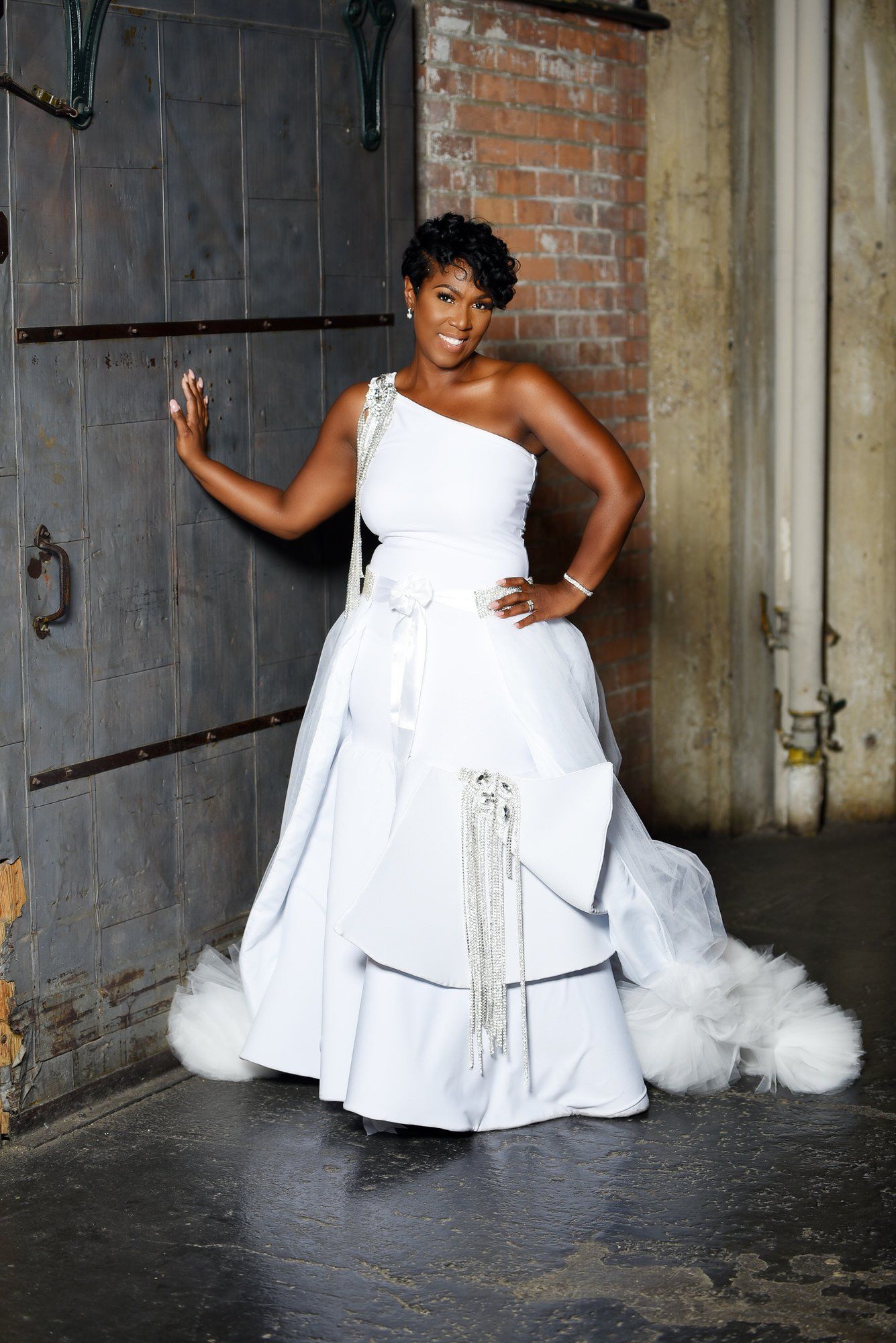a woman in a white wedding dress is standing in front of a brick wall