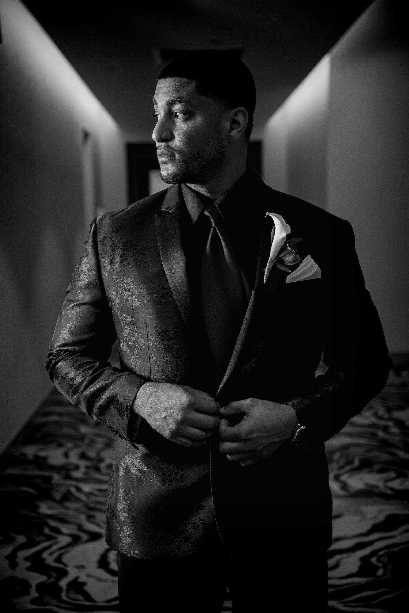 a man in a suit and tie is standing in a hallway adjusting his jacket .