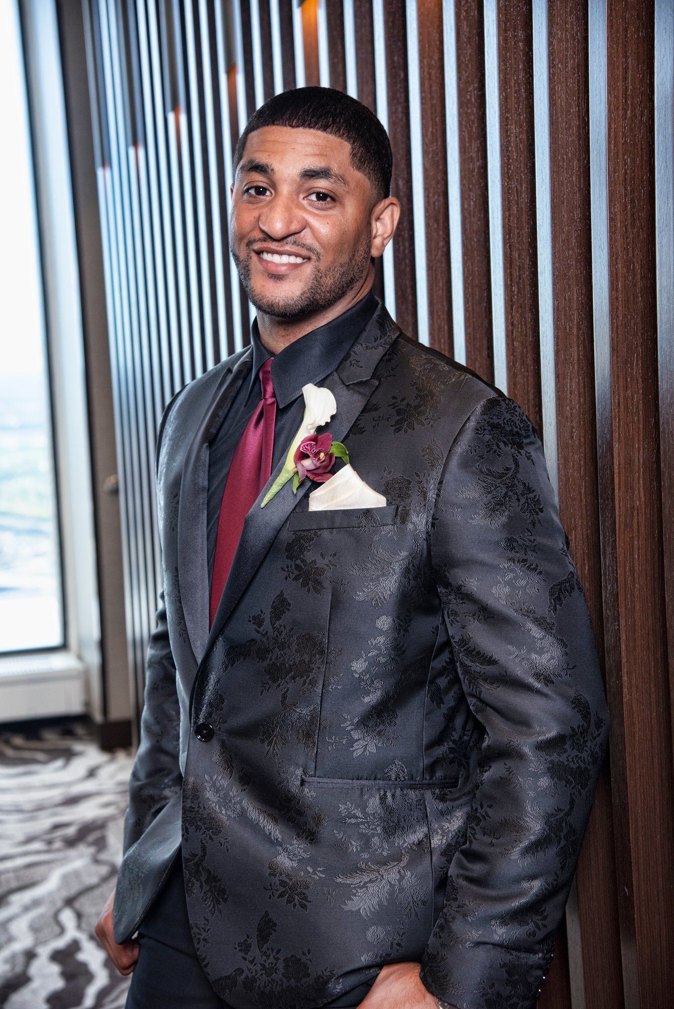 a man in a suit and tie is standing in front of a window .