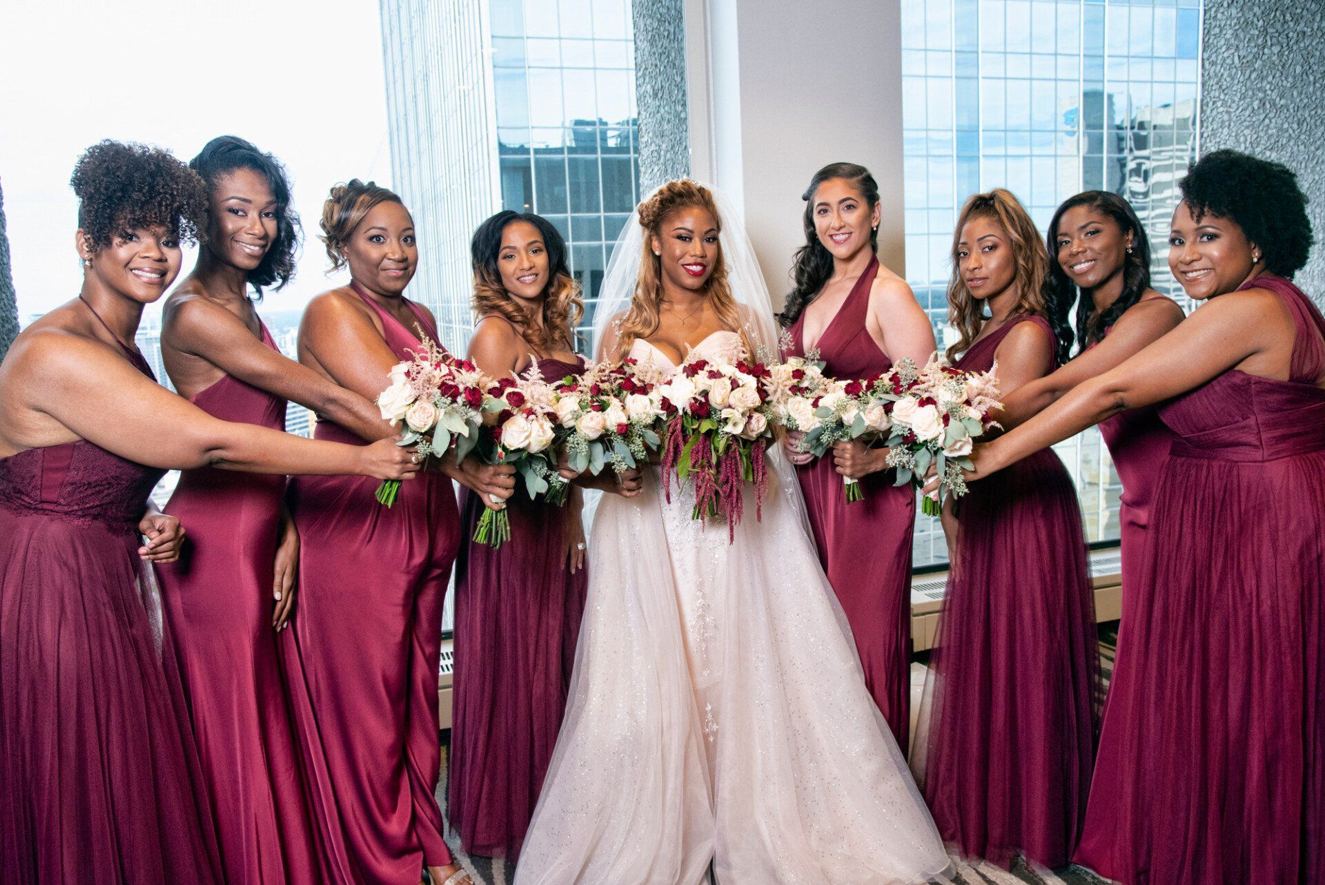 a bride and her bridesmaids are posing for a picture in front of a window .