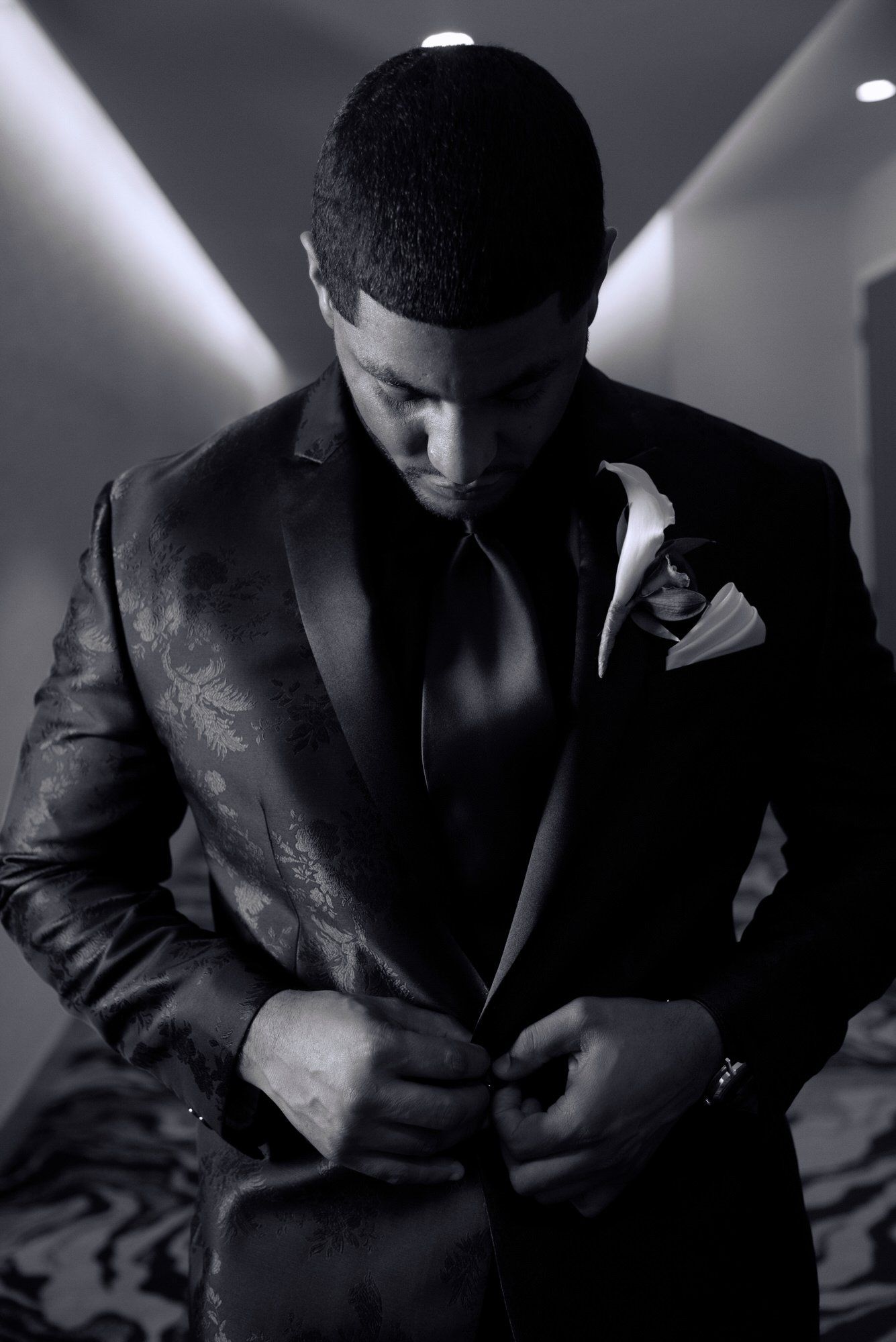 a man in a suit is adjusting his jacket in a black and white photo .
