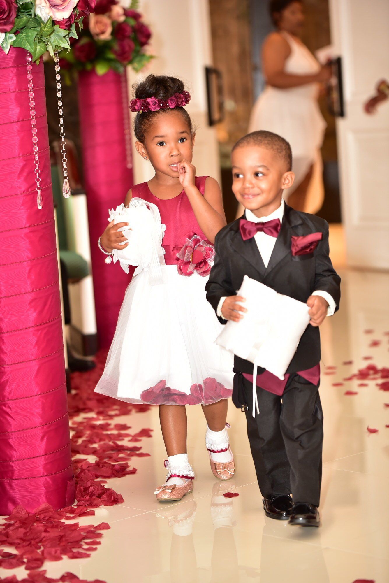 a flower girl and ring bearer are walking down the aisle at a wedding .
