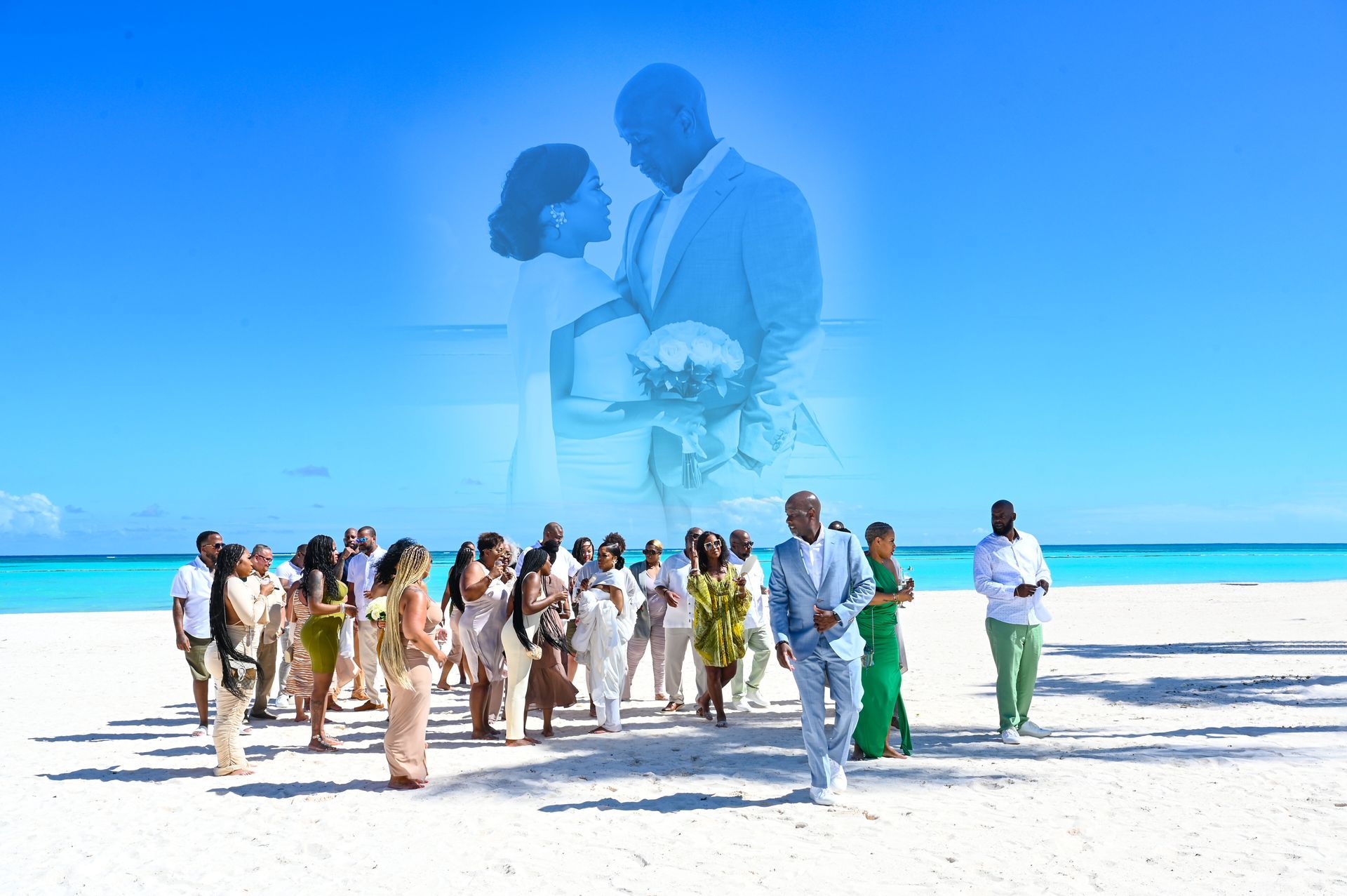 a group of people are standing on a beach with a bride and groom in the background .