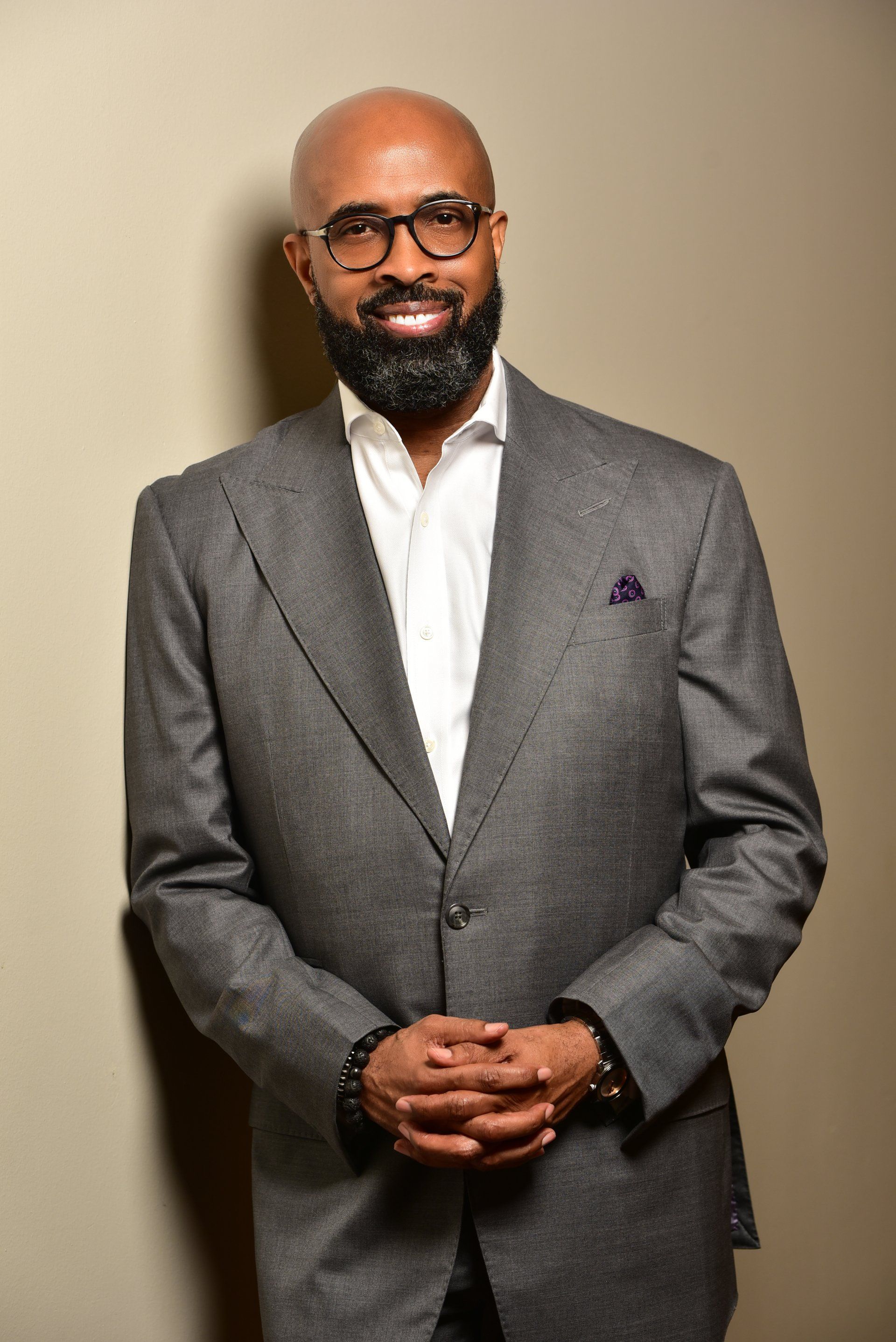 a bald man with a beard is wearing a suit and glasses .