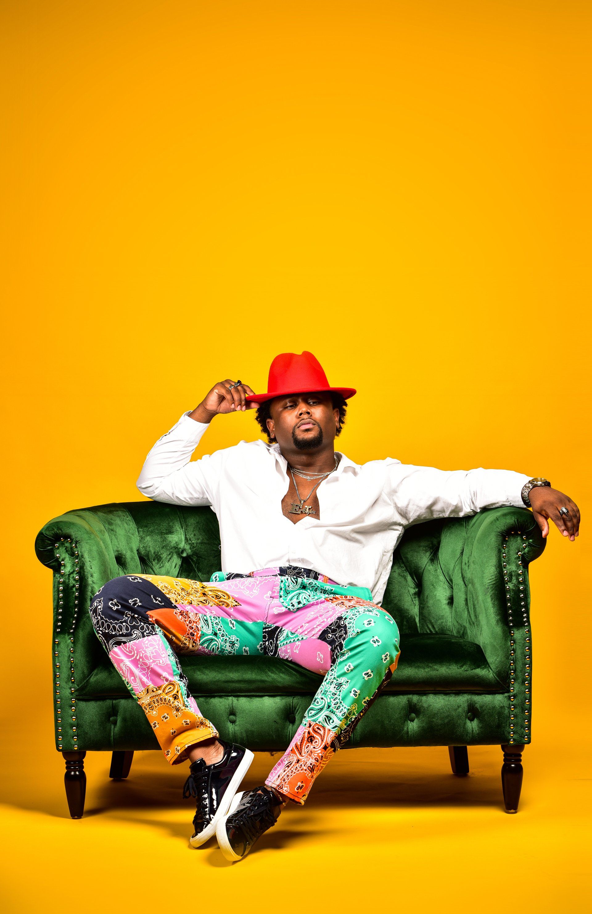 a man in a red hat is sitting on a green couch .