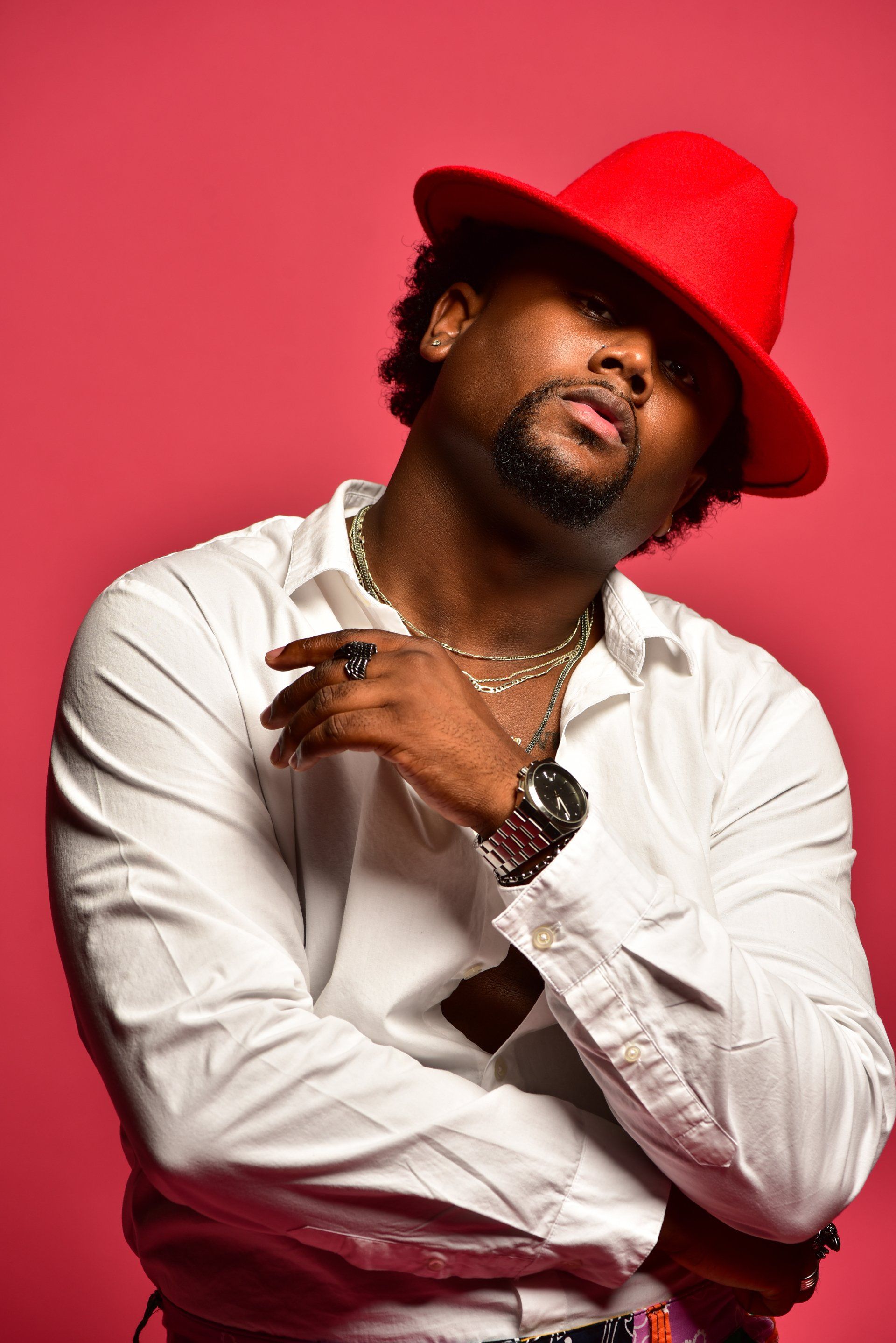 a man wearing a red hat and a white shirt is standing with his arms crossed .