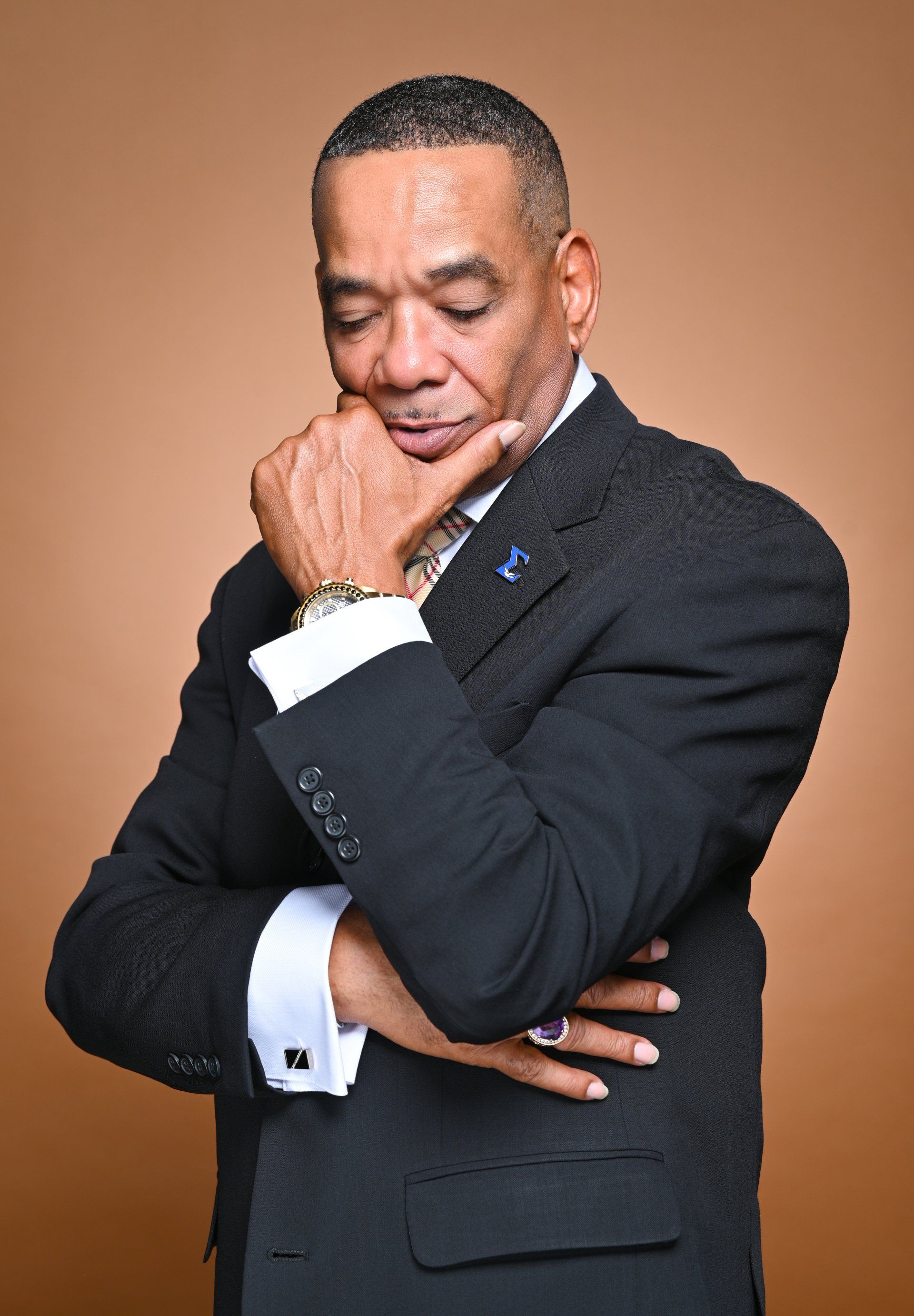 a man in a suit and tie is holding his hand to his chin .