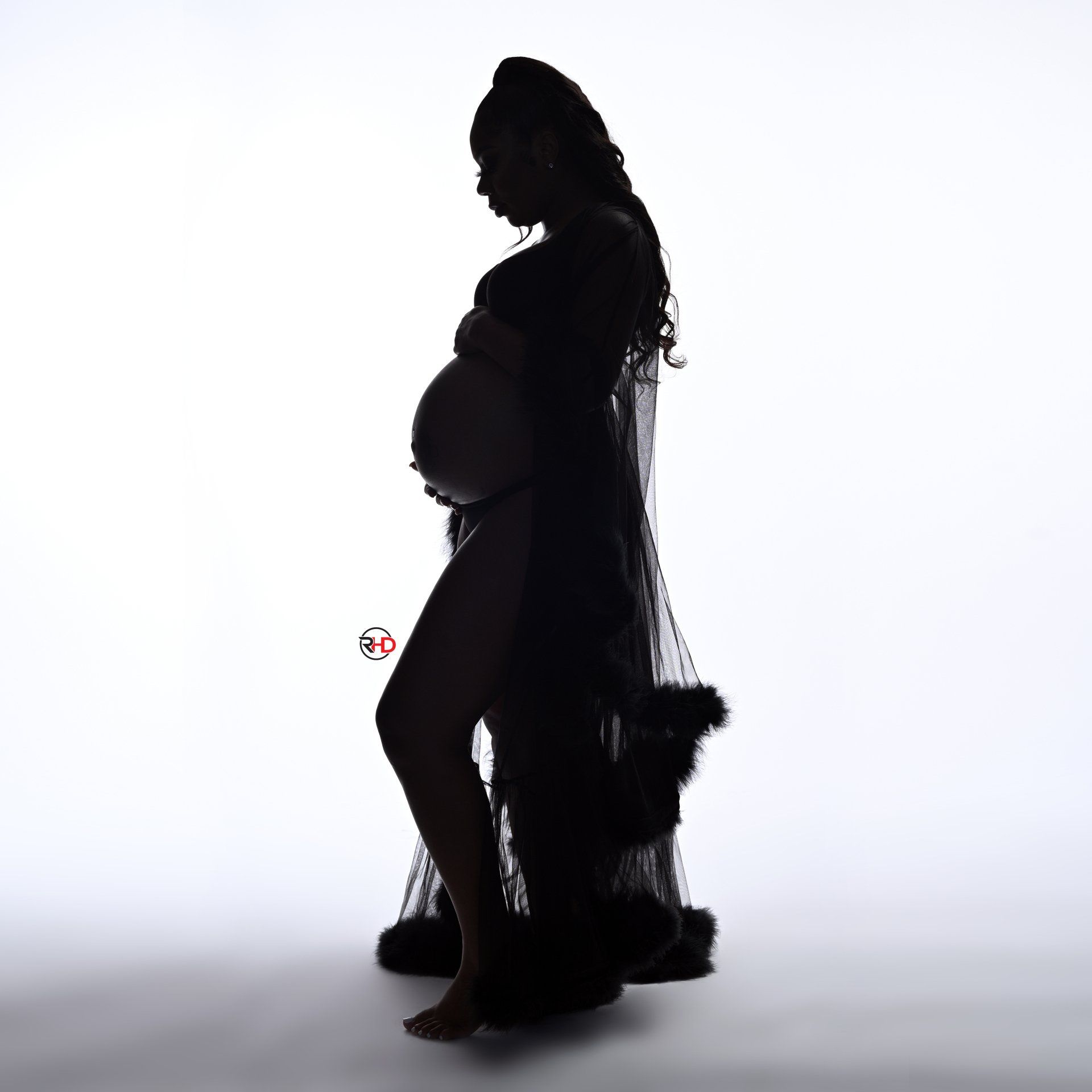 a silhouette of a pregnant woman in a black dress holding her belly .