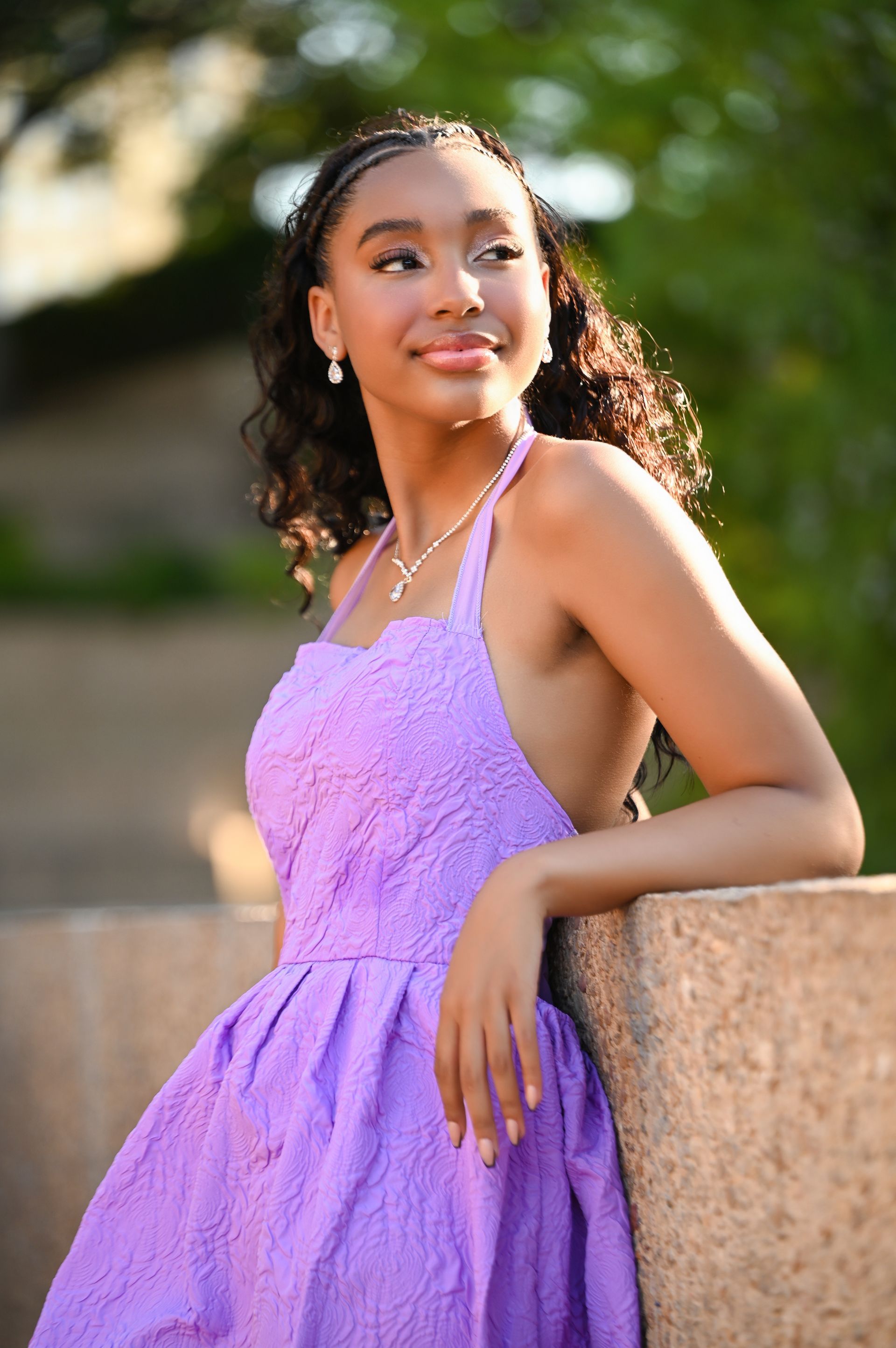 a woman in a purple dress is leaning against a wall .