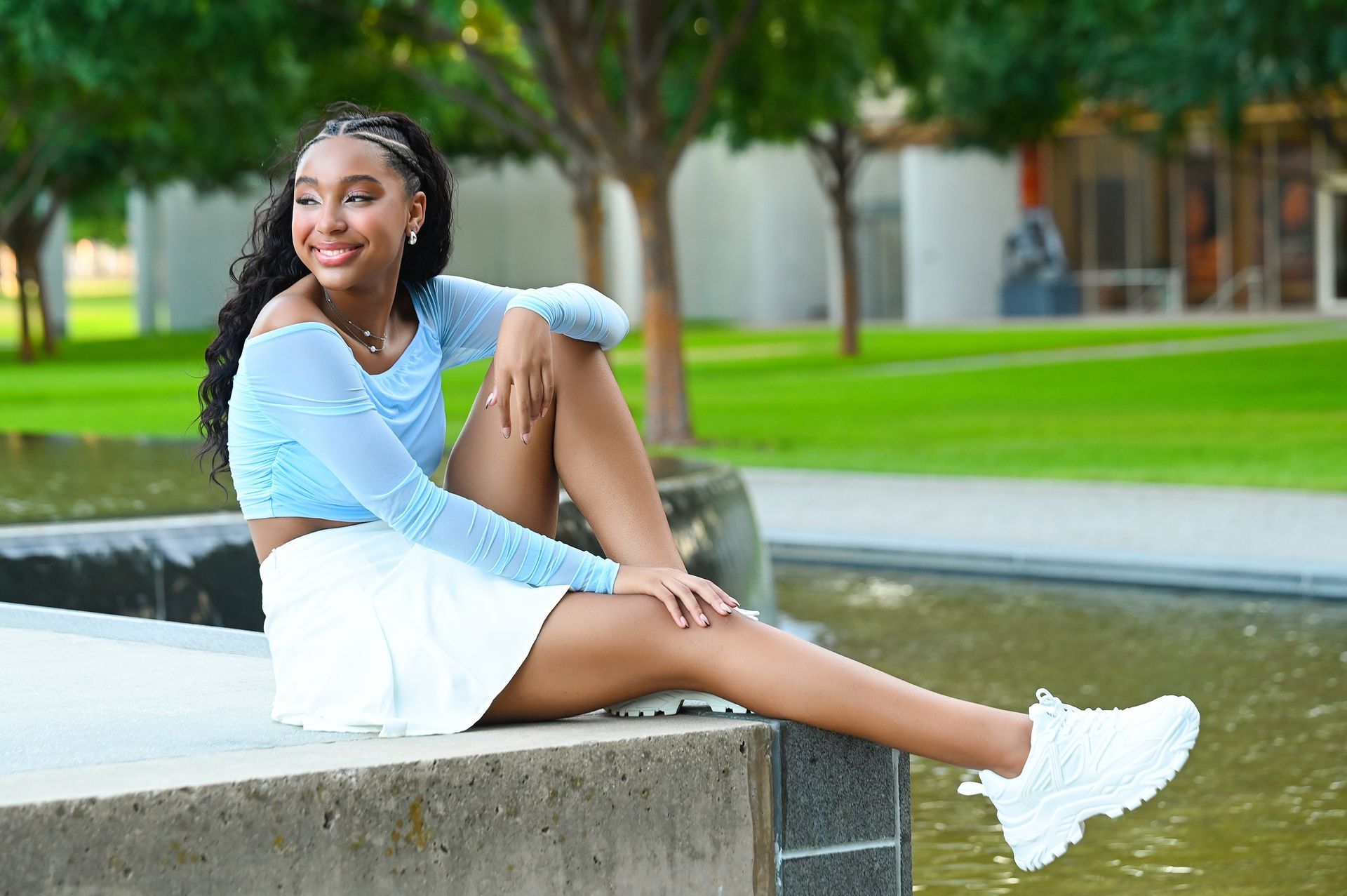 a young woman is sitting on a wall next to a waterfall .