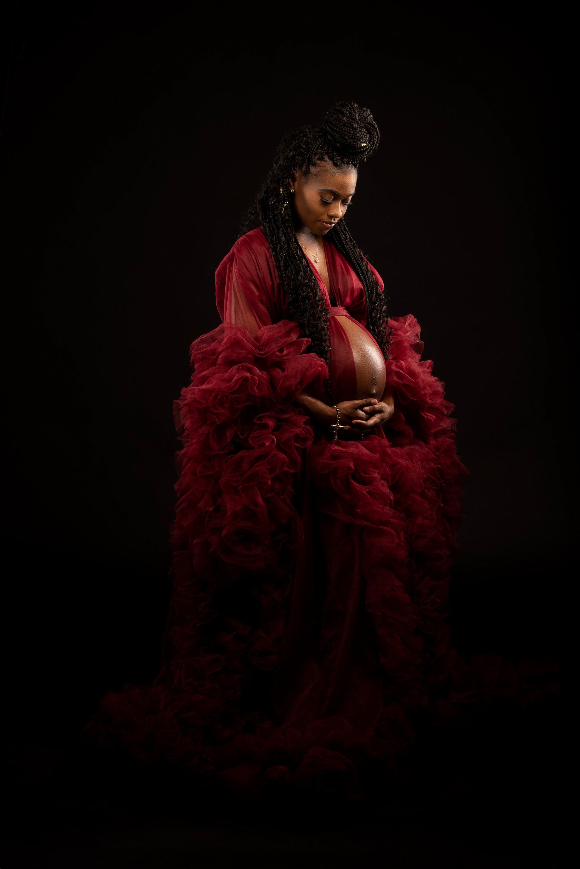 a pregnant woman in a red dress is holding her belly .
