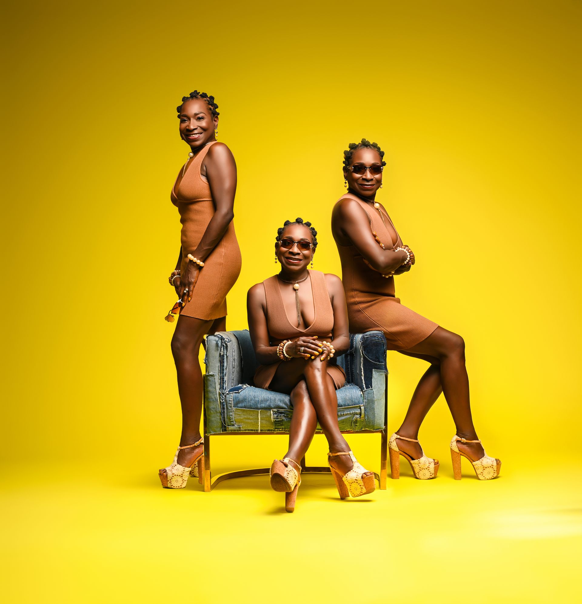 three women are posing for a picture while one of them is sitting in a chair .