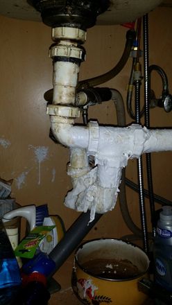 A sink with a lot of pipes underneath it and a bowl of water.