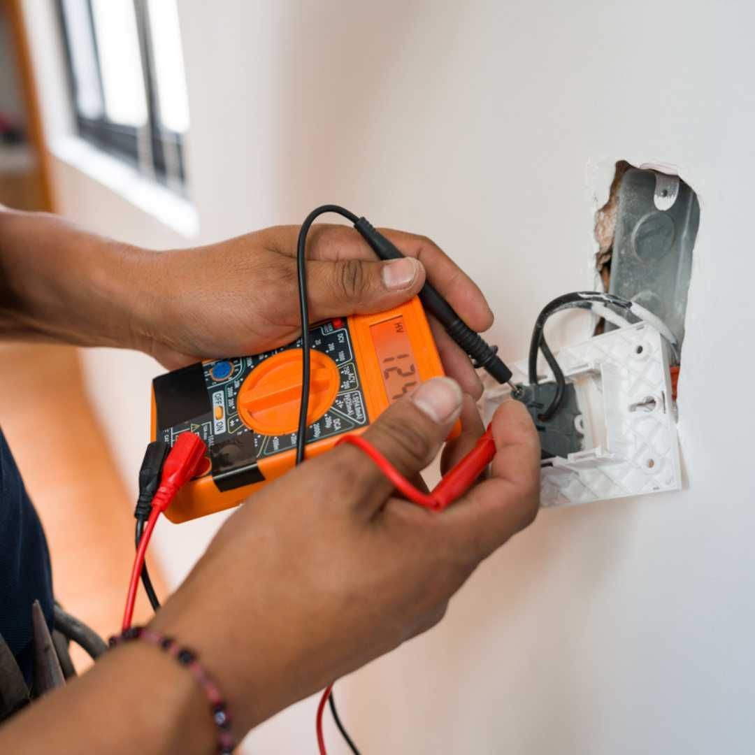 A person is using a multimeter to test an electrical outlet