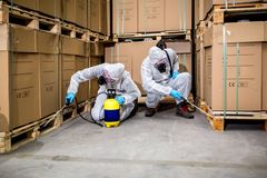 two pest control workers spraying a warehouse