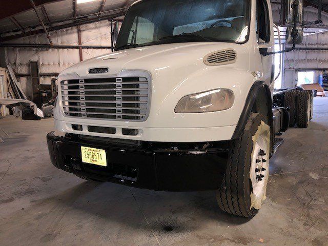 A white truck with a black bumper is parked in a garage.