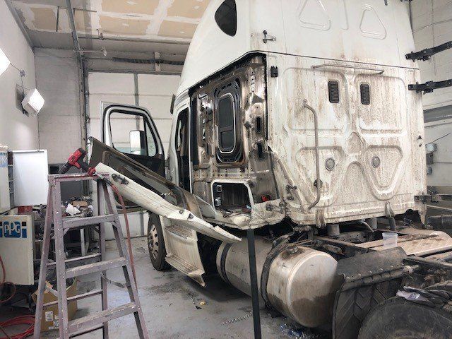 A white semi truck is being repaired in a garage.