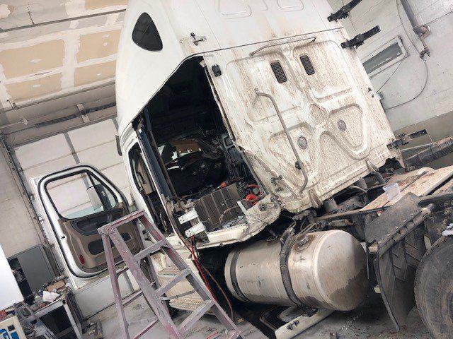 A white semi truck is being repaired in a garage.