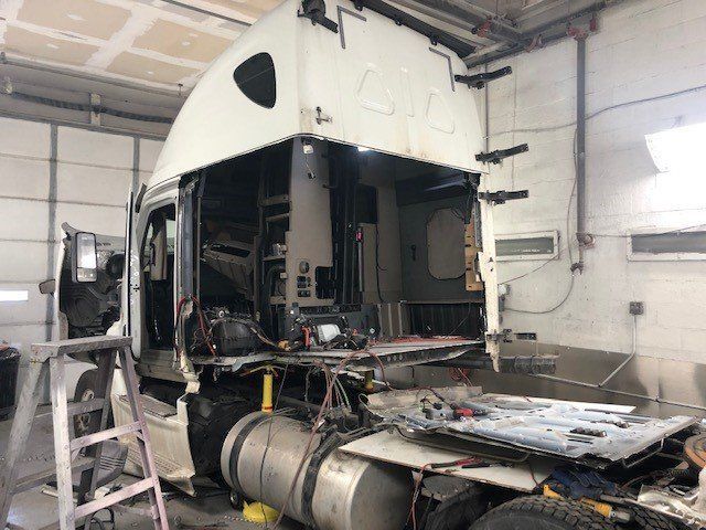 A semi truck is being repaired in a garage.