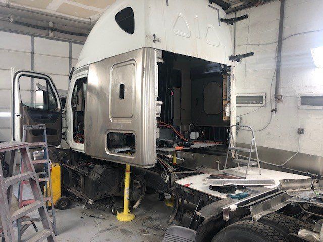 A semi truck is being repaired in a garage.