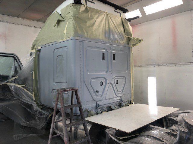 A truck is being painted in a paint booth.