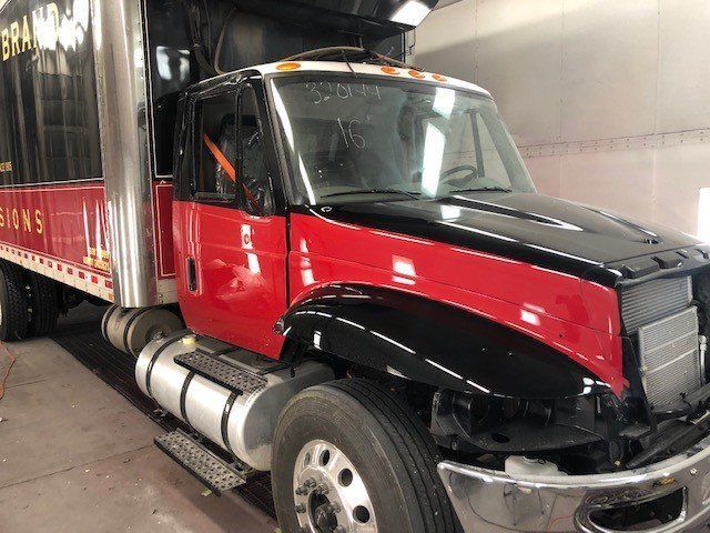 A red truck with a black hood is parked in a garage.