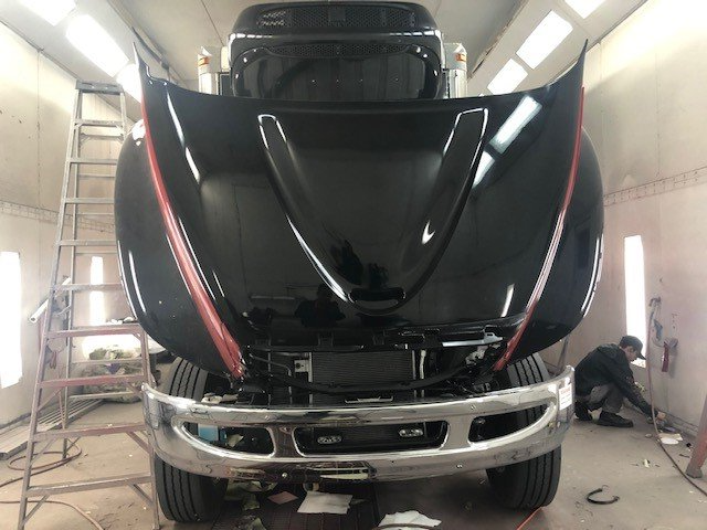 A black truck with the hood up is being painted.