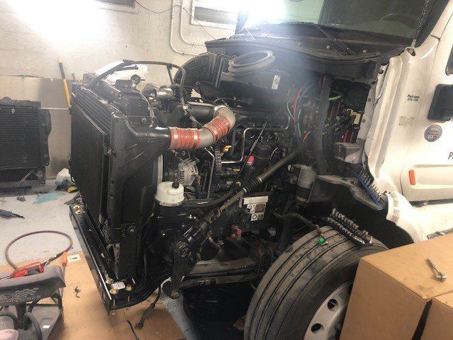 The engine of a semi truck is being worked on in a garage.