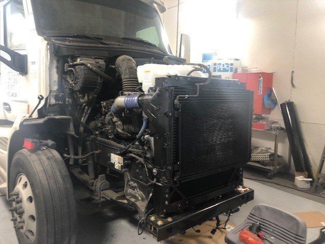 A semi truck with its hood open is sitting in a garage.